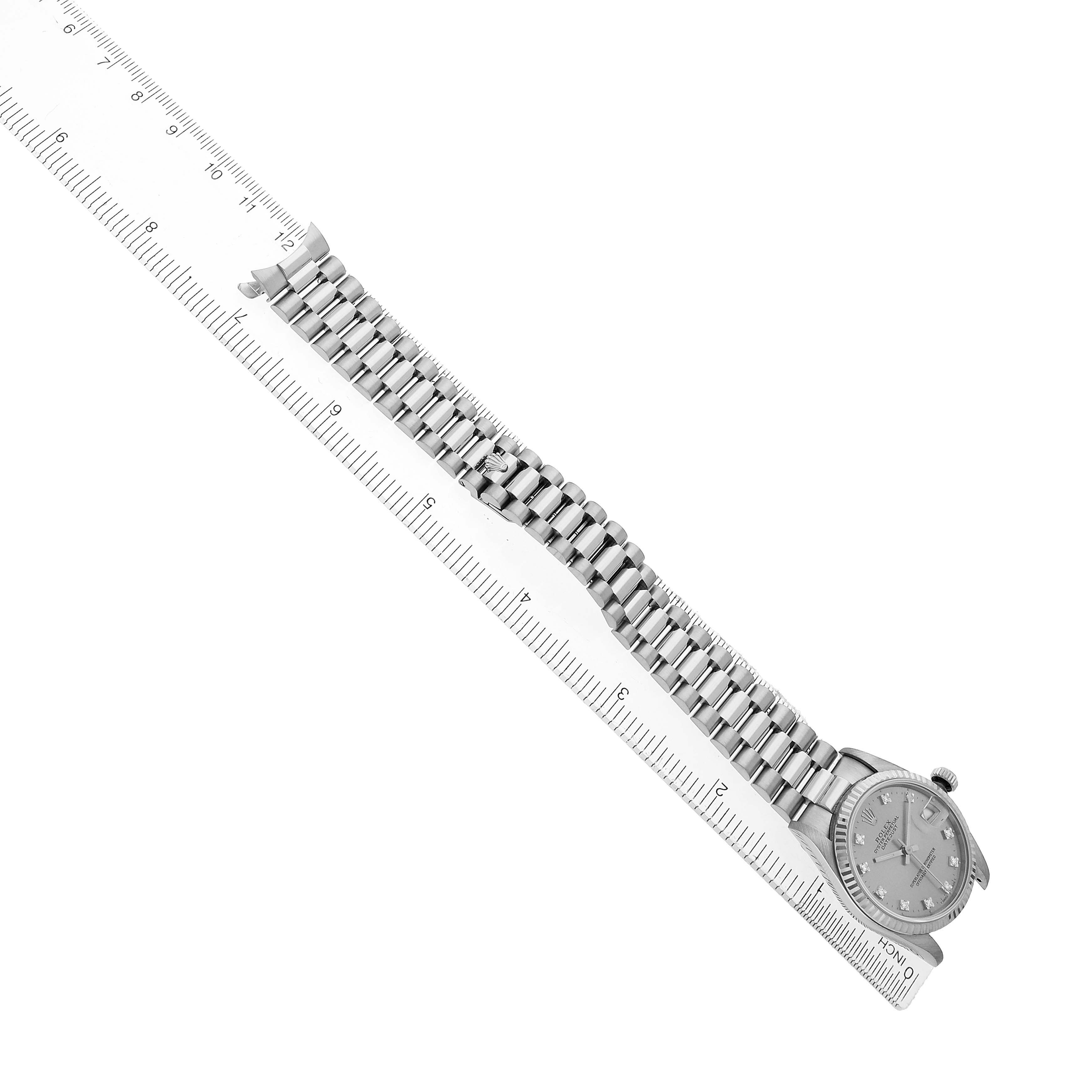 The image shows a Rolex President 68279 Women's White Gold Silver Dial model watch from a top angle, highlighting its band and face alongside a ruler for scale.