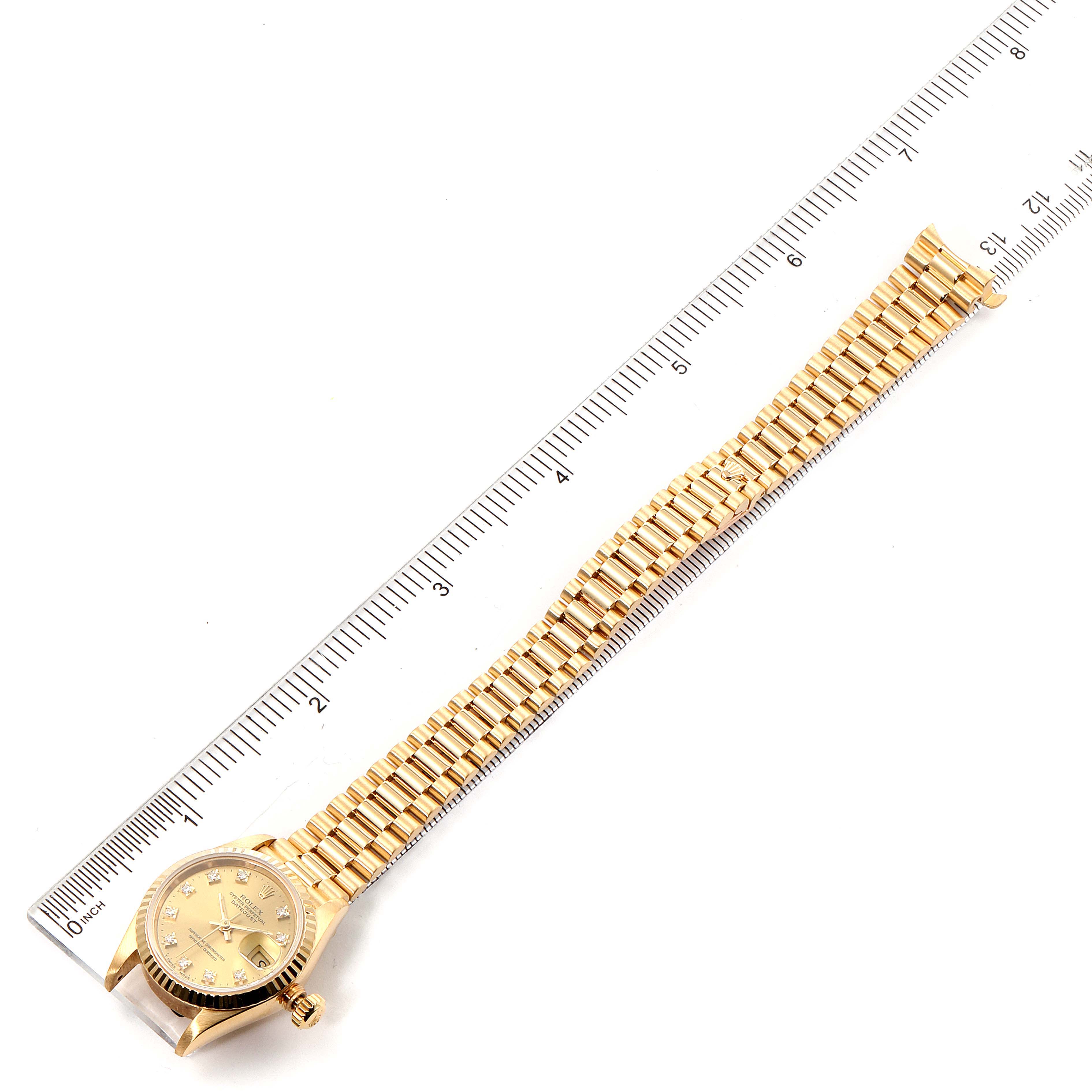 The Rolex President 69178 Women's Yellow Gold Champagne Dial 69178 Women's Yellow Gold Champagne Dial watch is shown fully extended with a ruler for scale, displaying its face, bezel, and bracelet.