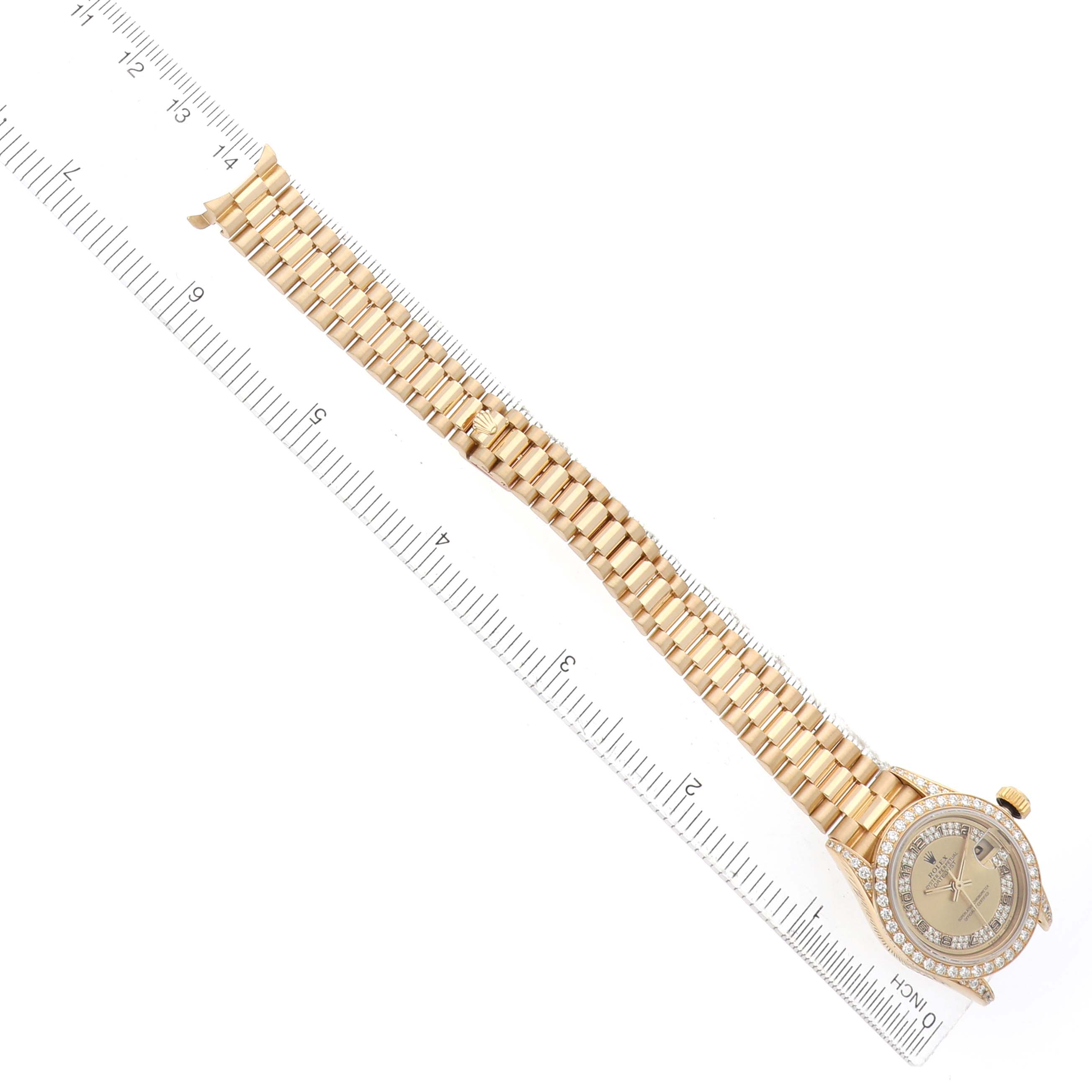 The Rolex President 69158 Women's Yellow Gold Champagne Dial watch is shown from a top view, displaying the full bracelet and watch face near a ruler.