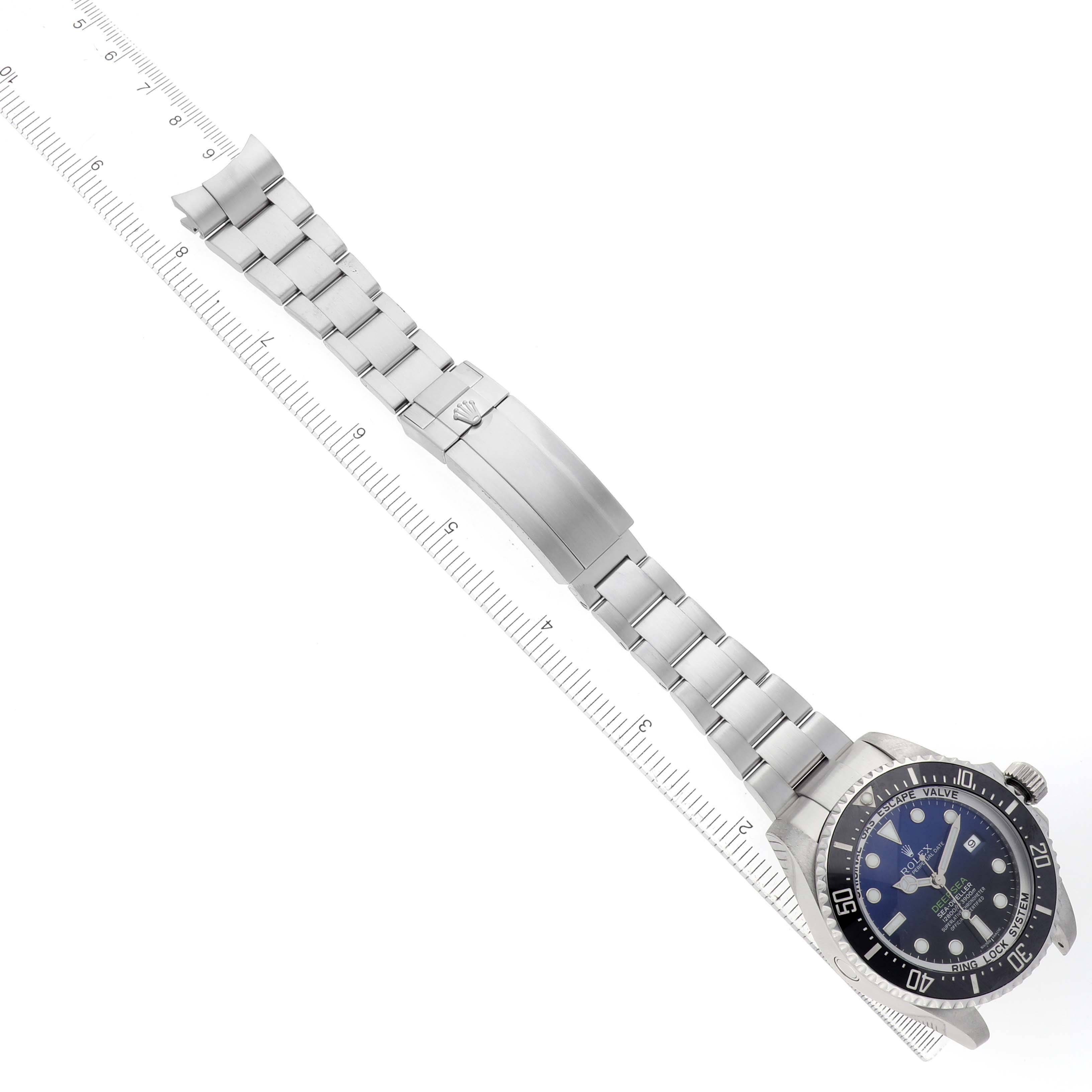 The Rolex Sea-Dweller 116660 Men's Stainless Steel Blue Dial watch is shown diagonally with its dial, bracelet, and clasp visible alongside a ruler.