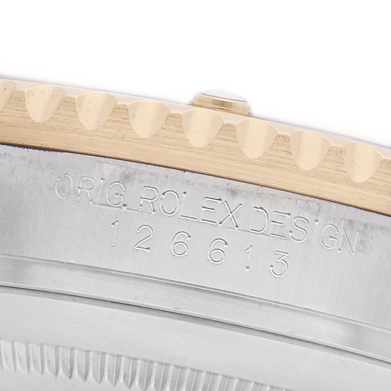 The image shows the edge of a Rolex Submariner 126613 Men's Steel and Gold (two tone) Blue Dial watch with visible bezel teeth and case engraving.