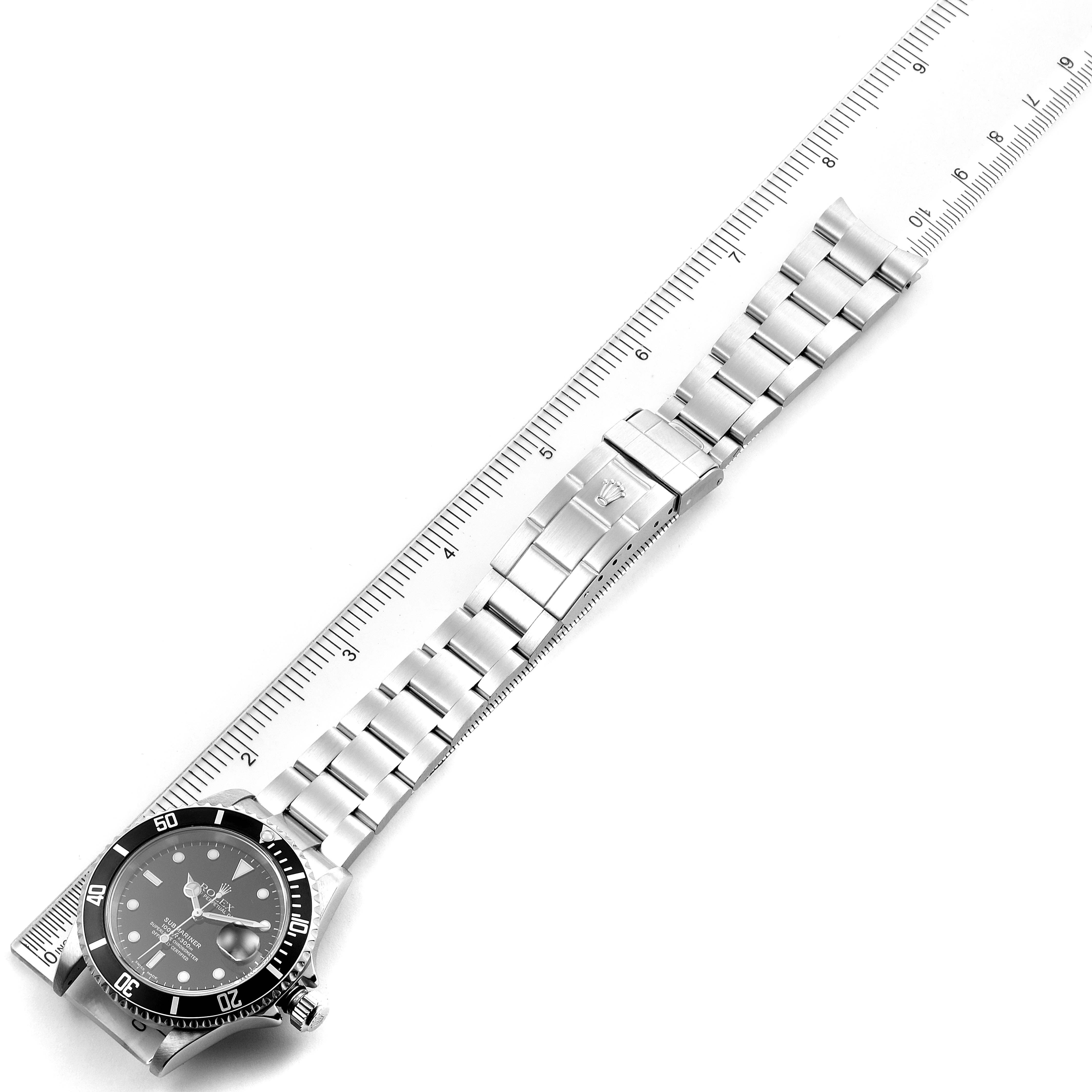 The Rolex Submariner 16610 Men's Stainless Steel Black Dial 16610 Men's Stainless Steel Black Dial watch is shown from an overhead angle along with a measuring ruler.