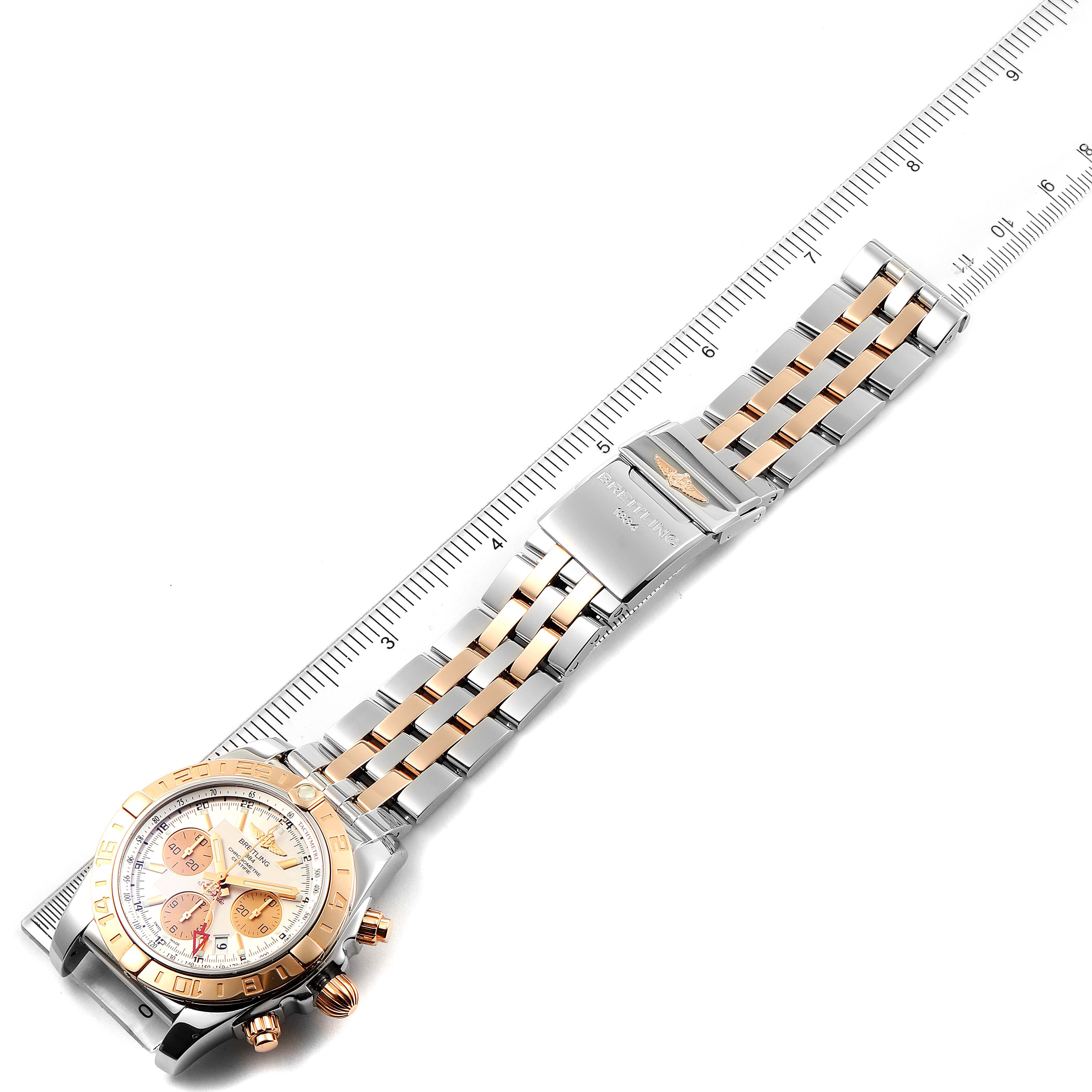 The image shows a top-down view of a Breitling Chronomat CB0420 Men's Steel and Gold (two tone) Silver Dial CB0420 Men's Steel and Gold (two tone) Silver Dial watch, focusing on the full bracelet, clasp, and watch face along with a ruler for size.