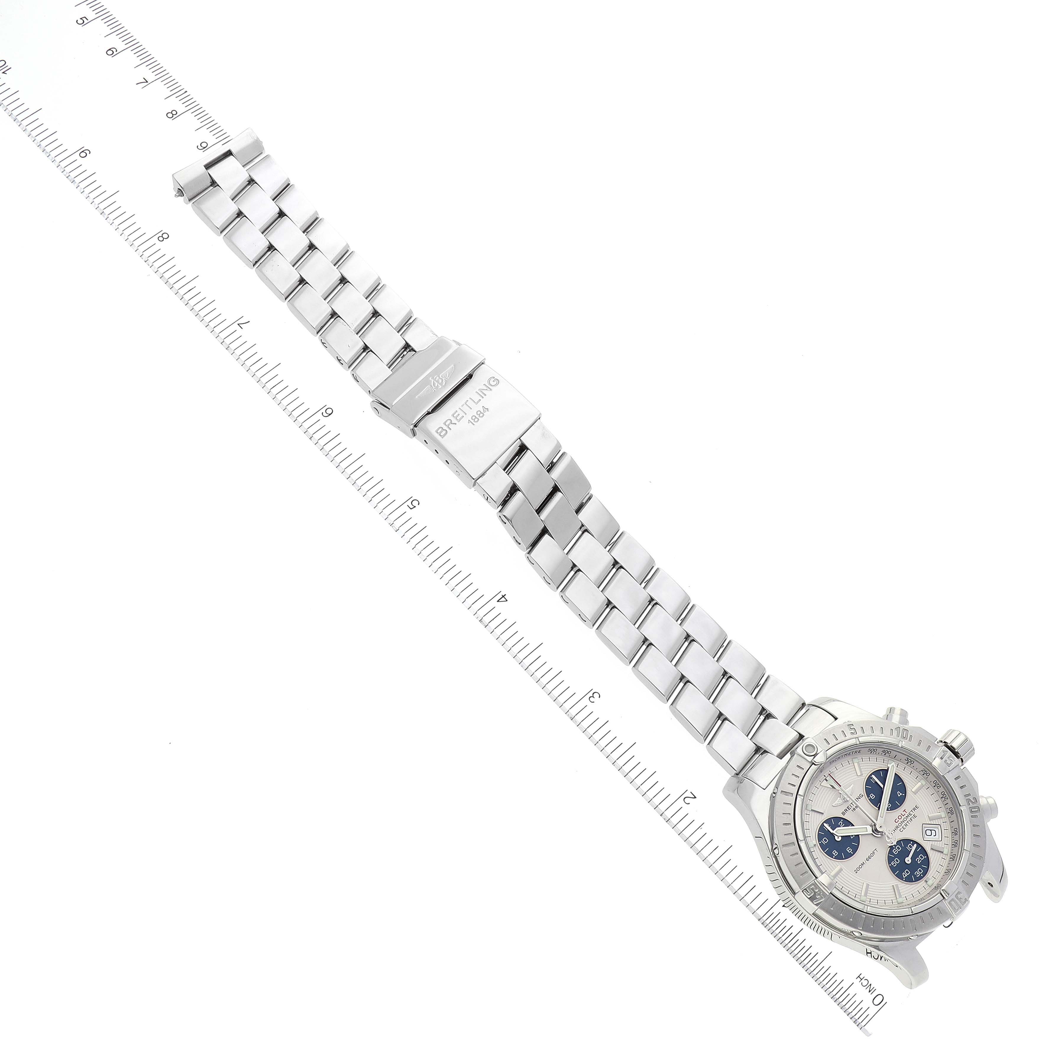 The image shows a top-down view of a Breitling Colt A73380 Men's Stainless Steel White Dial A73380 Men's Stainless Steel White Dial watch, including its face, steel bracelet, and clasp, alongside a ruler for scale.