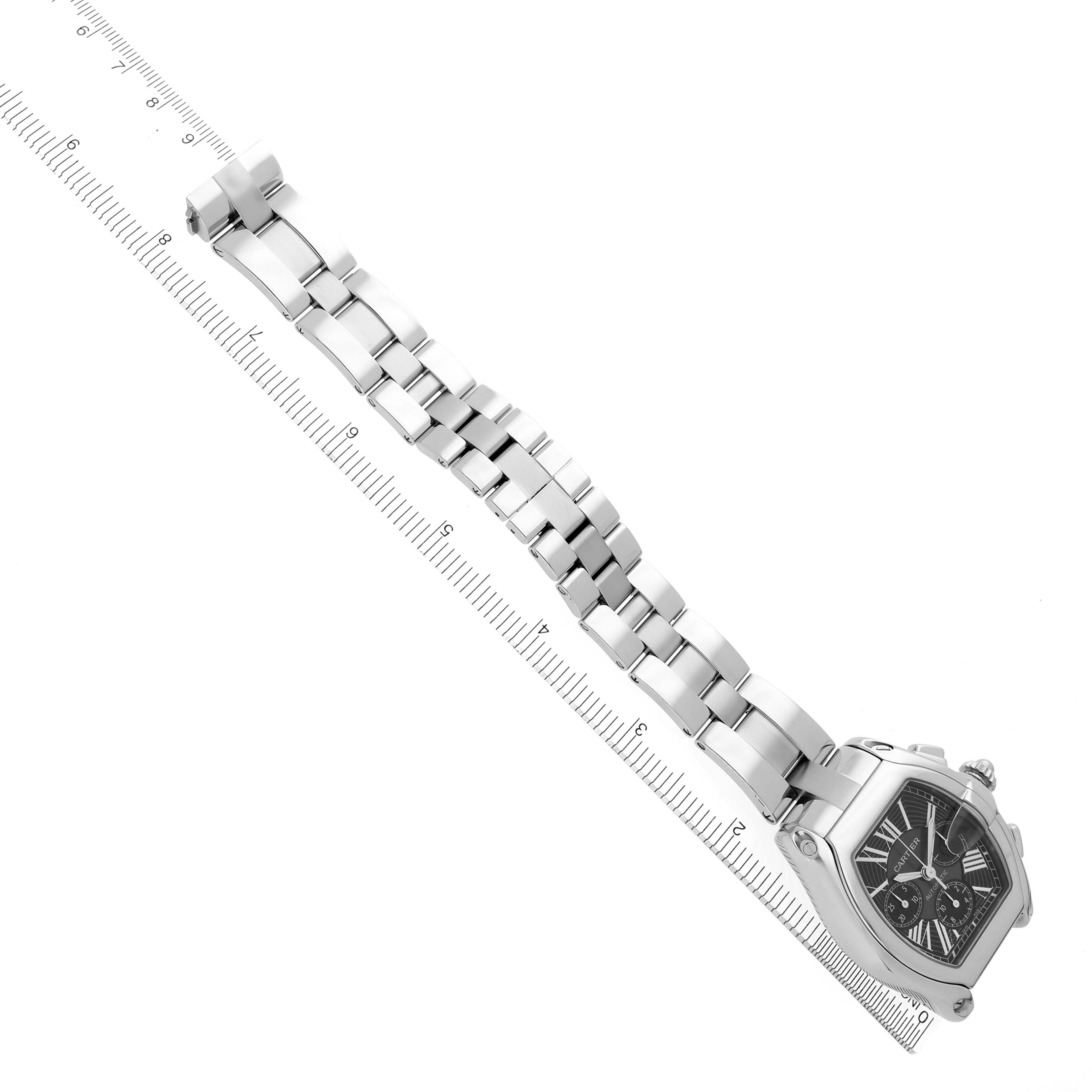 The image shows a Cartier Roadster W62020X6 Men's Stainless Steel Black Dial W62020X6 Men's Stainless Steel Black Dial watch at an angle, highlighting its case, dial, and stainless steel bracelet alongside a ruler.