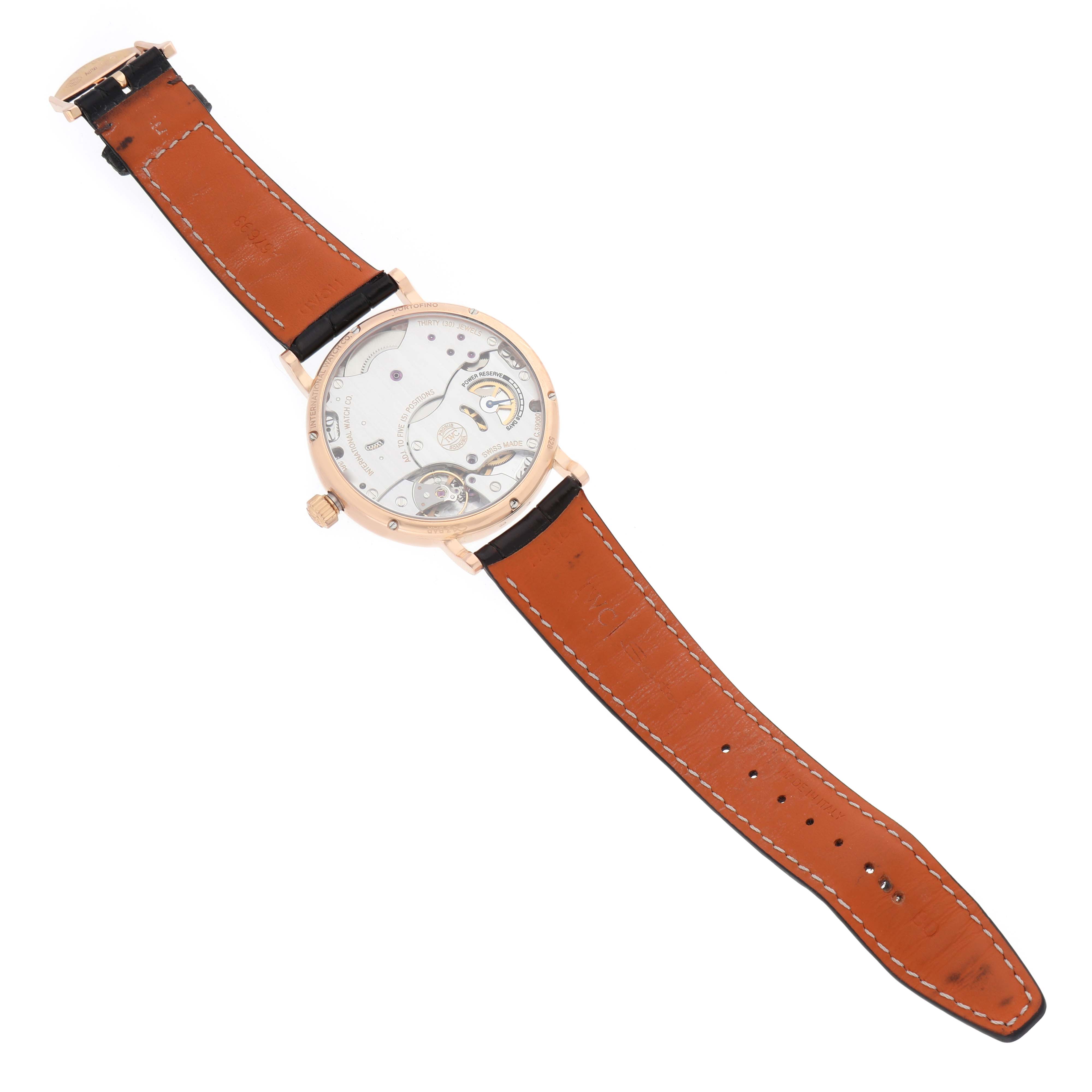 The IWC Portofino IW511101 Men's Rose Gold Silver Dial watch is shown from the back, displaying its mechanism and brown leather strap.