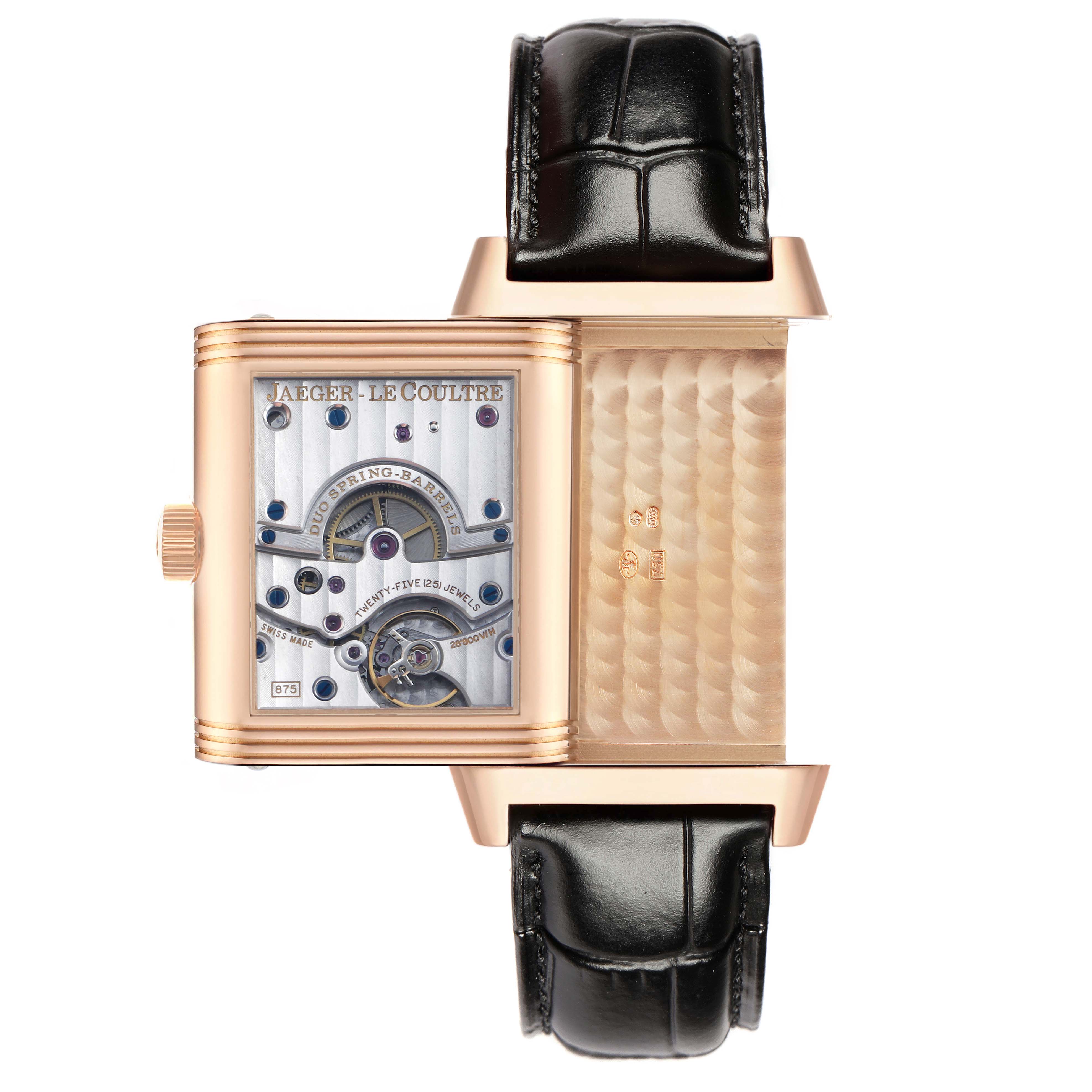 The image shows a Jaeger-LeCoultre Reverso watch with its case flipped open, revealing the intricate movement mechanism.