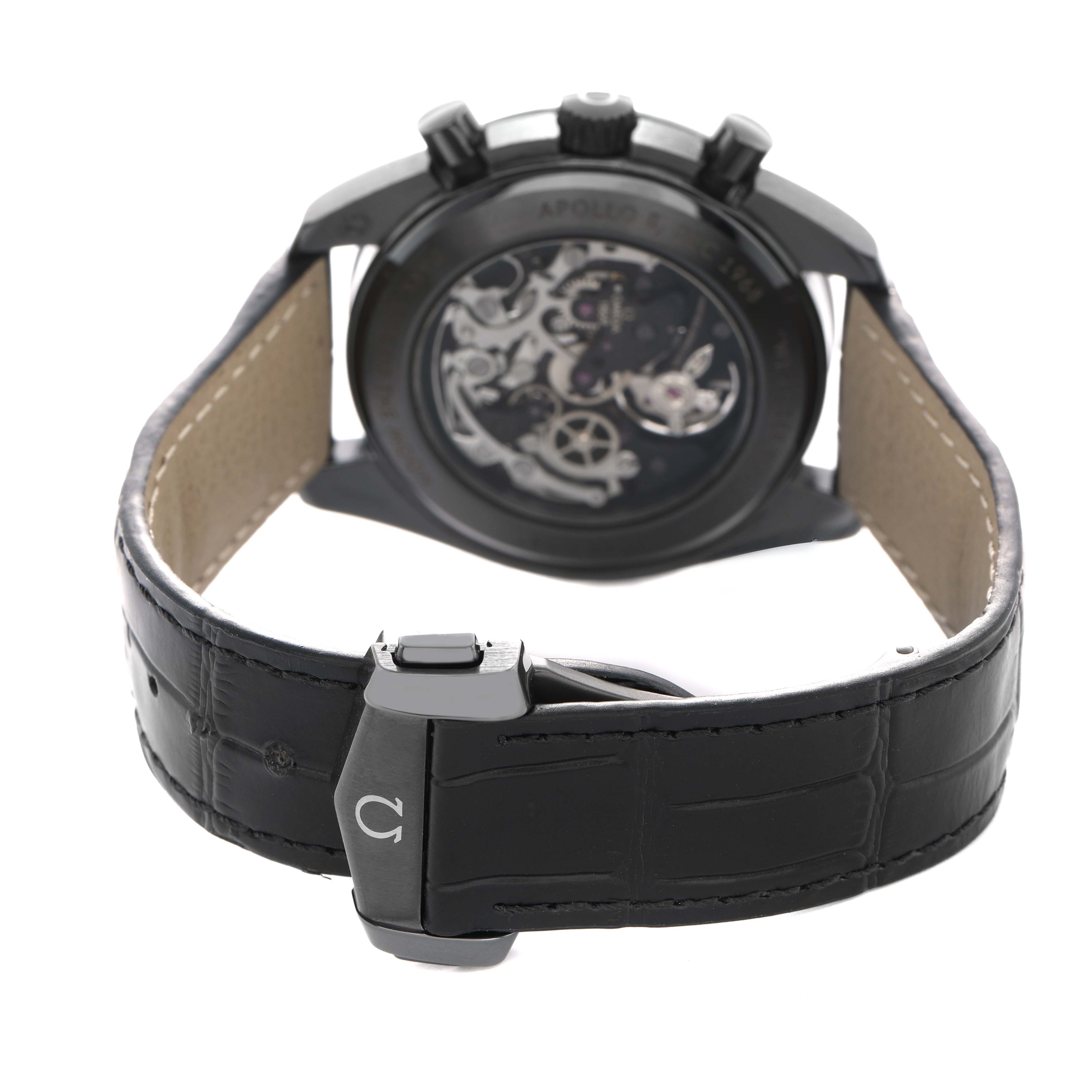 The image shows the back view of an Omega Speedmaster 311.92.44.30.01.001 Men's Ceramic Black Dial, highlighting its open case back and leather strap with a clasp.