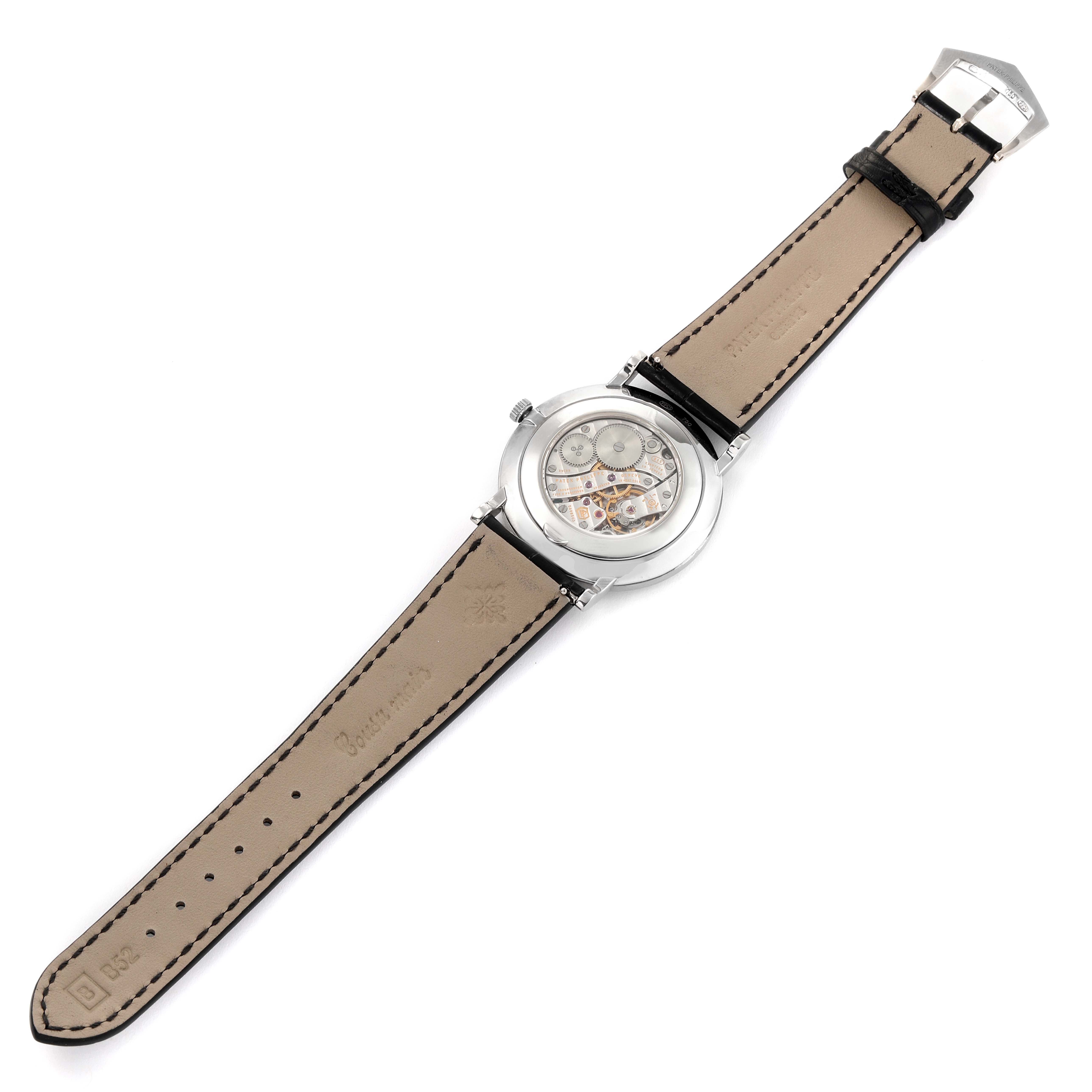 The image depicts the backside of a Patek Philippe Calatrava 5116G Men's White Gold White Dial 5116G Men's White Gold White Dial watch showing its exposed mechanism and leather strap.