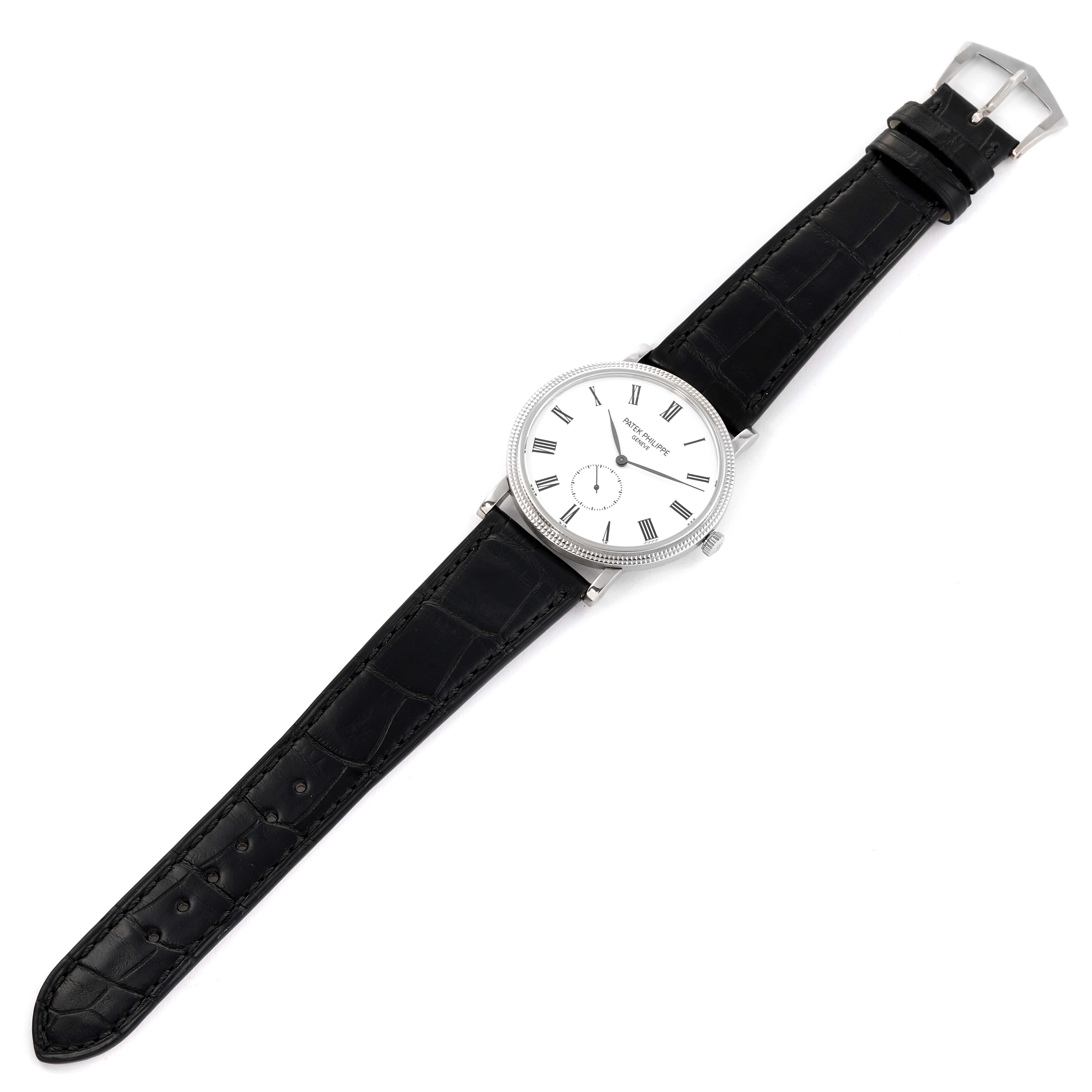 The image shows a top-down view of a Patek Philippe Calatrava 5116G Men's White Gold White Dial 5116G Men's White Gold White Dial watch, displaying its white dial, black leather strap, and buckle.