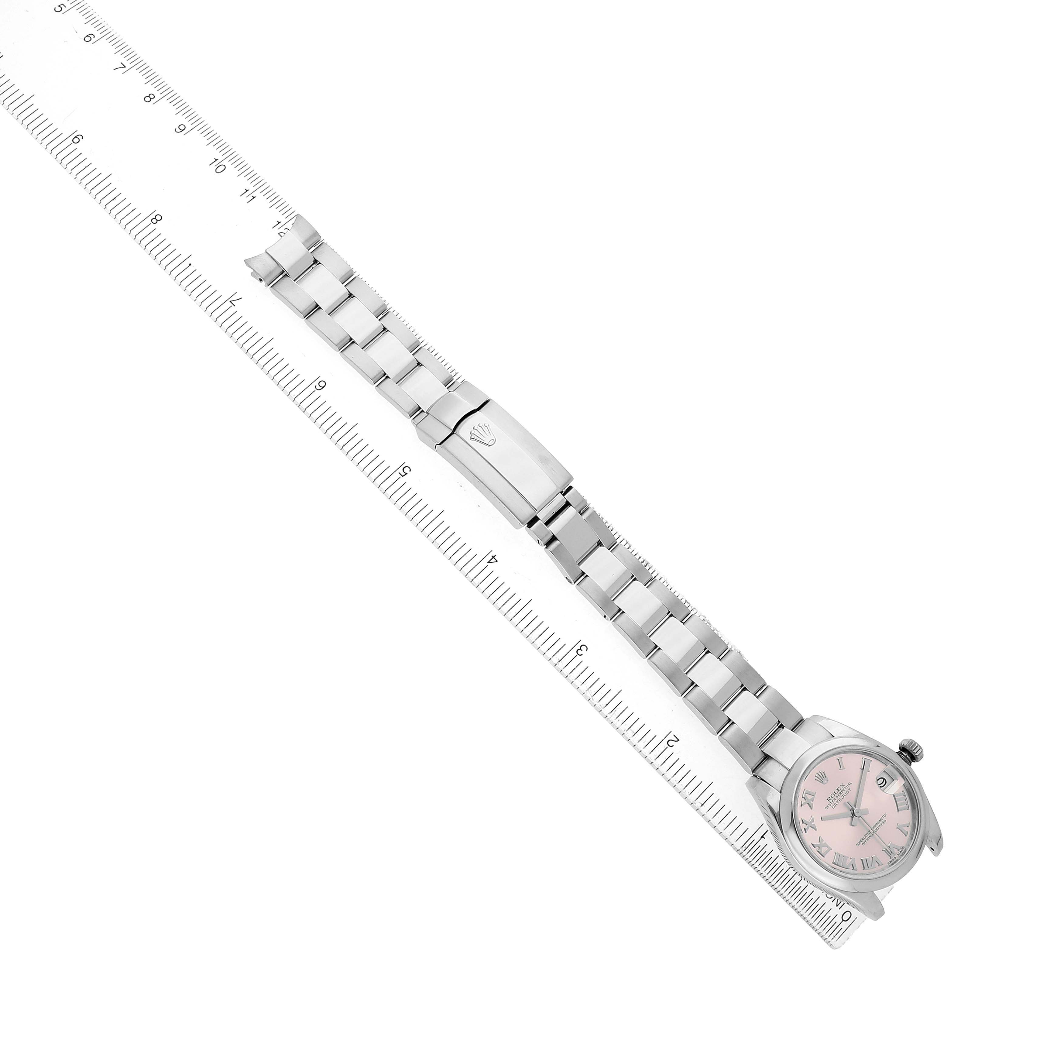 The Rolex Mid-Size 178240 Women's Stainless Steel Pink Dial watch is shown from a top-down angle, displaying the bracelet, clasp, and pink dial next to a ruler.