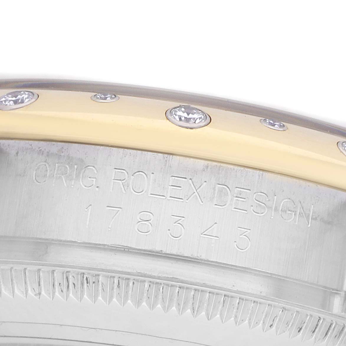The image shows a close-up side view of the bezel and case side of a Rolex mid-size watch, with diamonds and engraved design details.