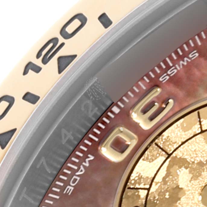 The image shows a close-up of a Rolex Daytona 116503 Men's Steel and Gold (two tone) Mother of Pearl Dial 116503 Men's Steel and Gold (two tone) Mother of Pearl Dial bezel and part of the dial with numerals and markings.