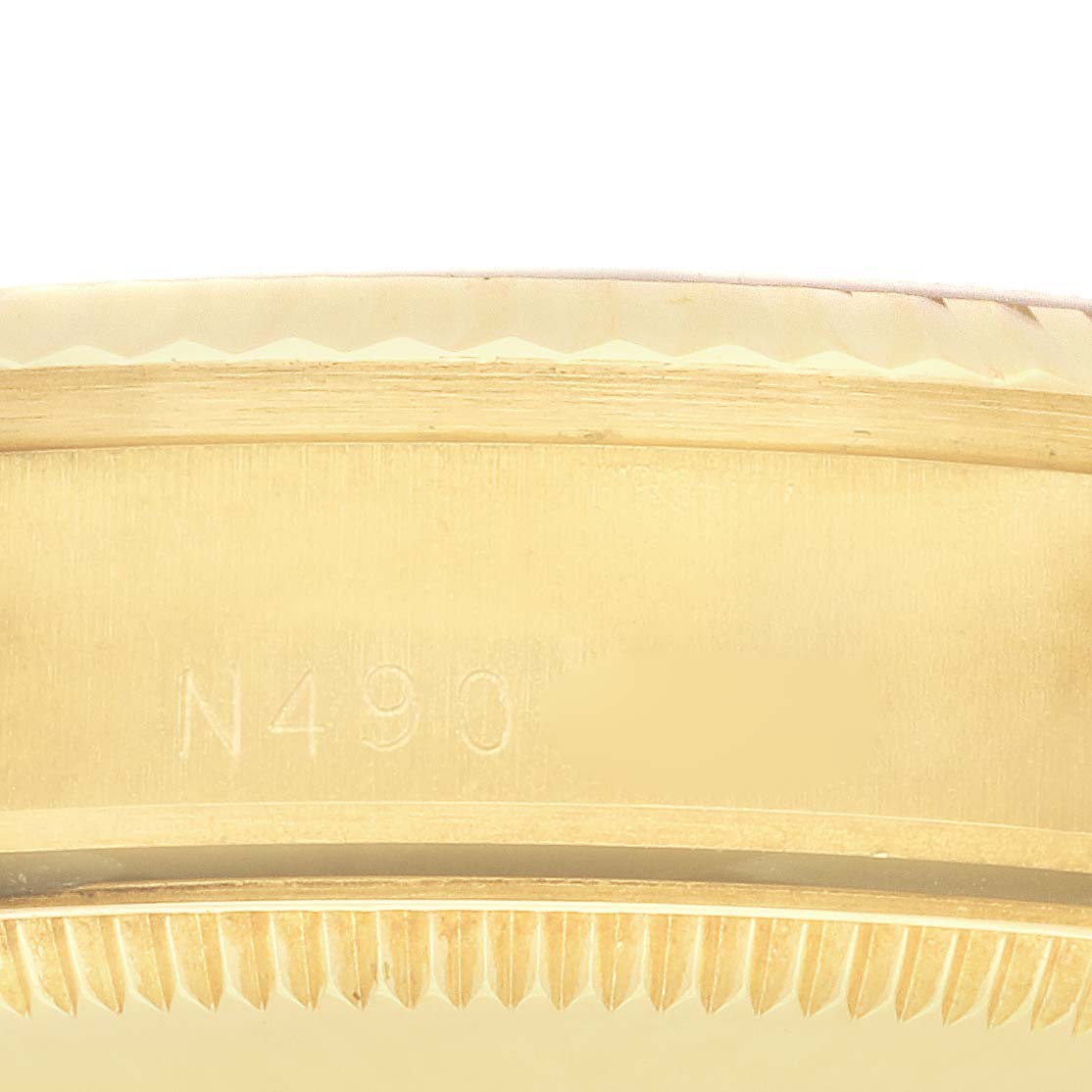 The image shows the side of the bezel of a Rolex President 68278 Women's Yellow Gold Silver Dial 68278 Women's Yellow Gold Silver Dial model, highlighting its serrated edge and part of the case.