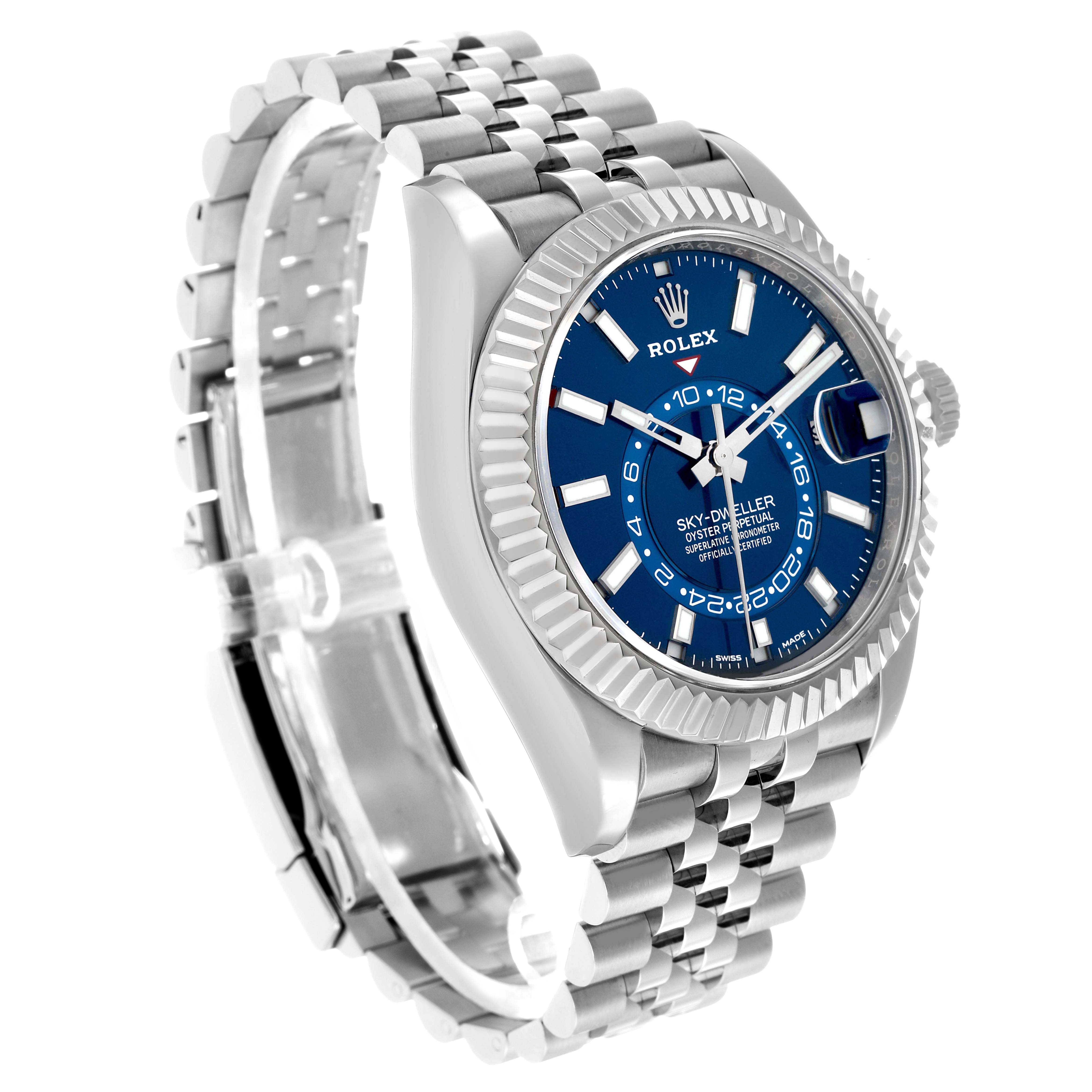 The Rolex Sky-Dweller 326934 Men's Stainless Steel Blue Dial watch is shown at a three-quarter angle, highlighting its blue dial, fluted bezel, and Jubilee bracelet.