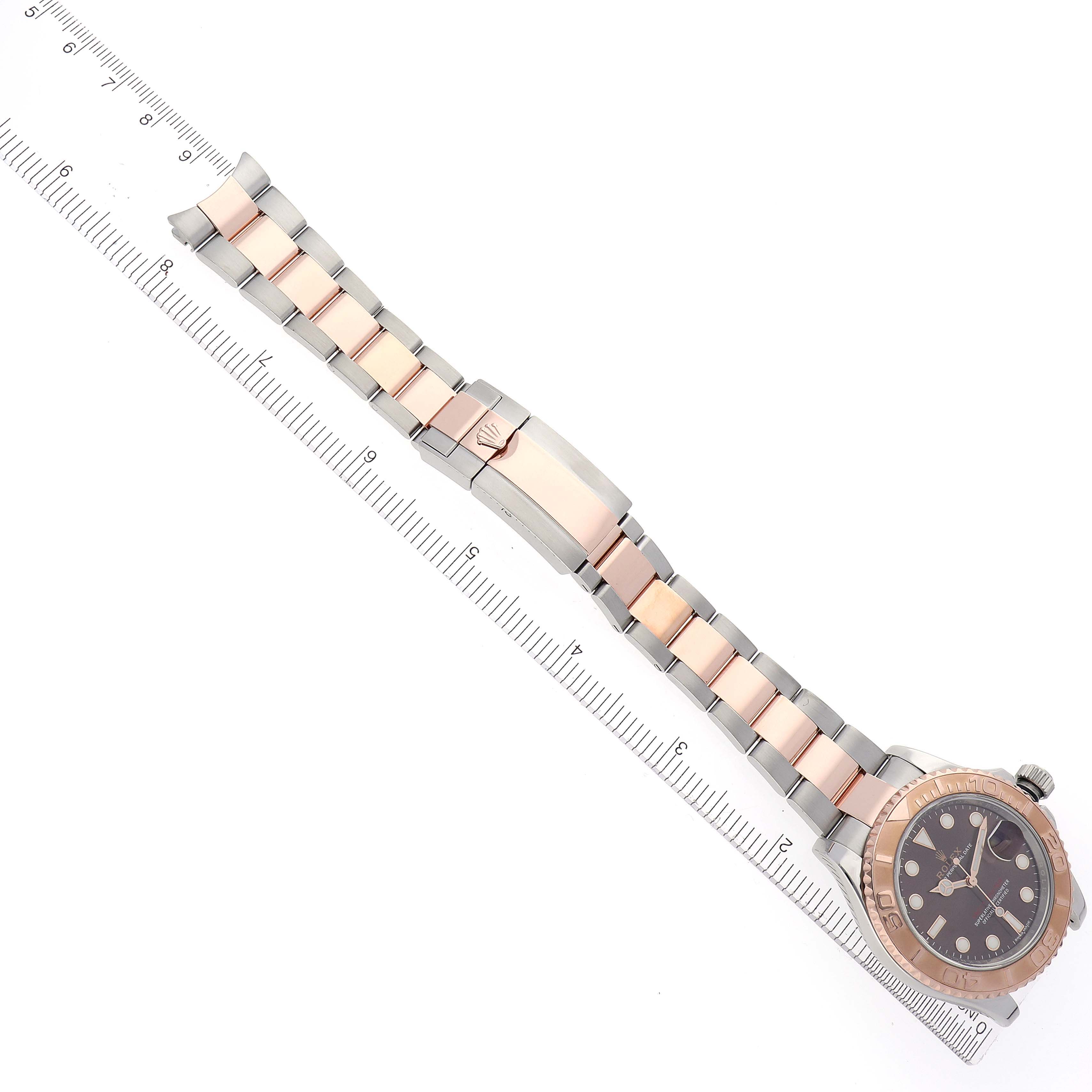 The Rolex Yacht-Master 116621 Men's Steel and Gold (two tone) Brown Dial watch is shown from above, displaying the full bracelet and part of the face, with a ruler alongside.