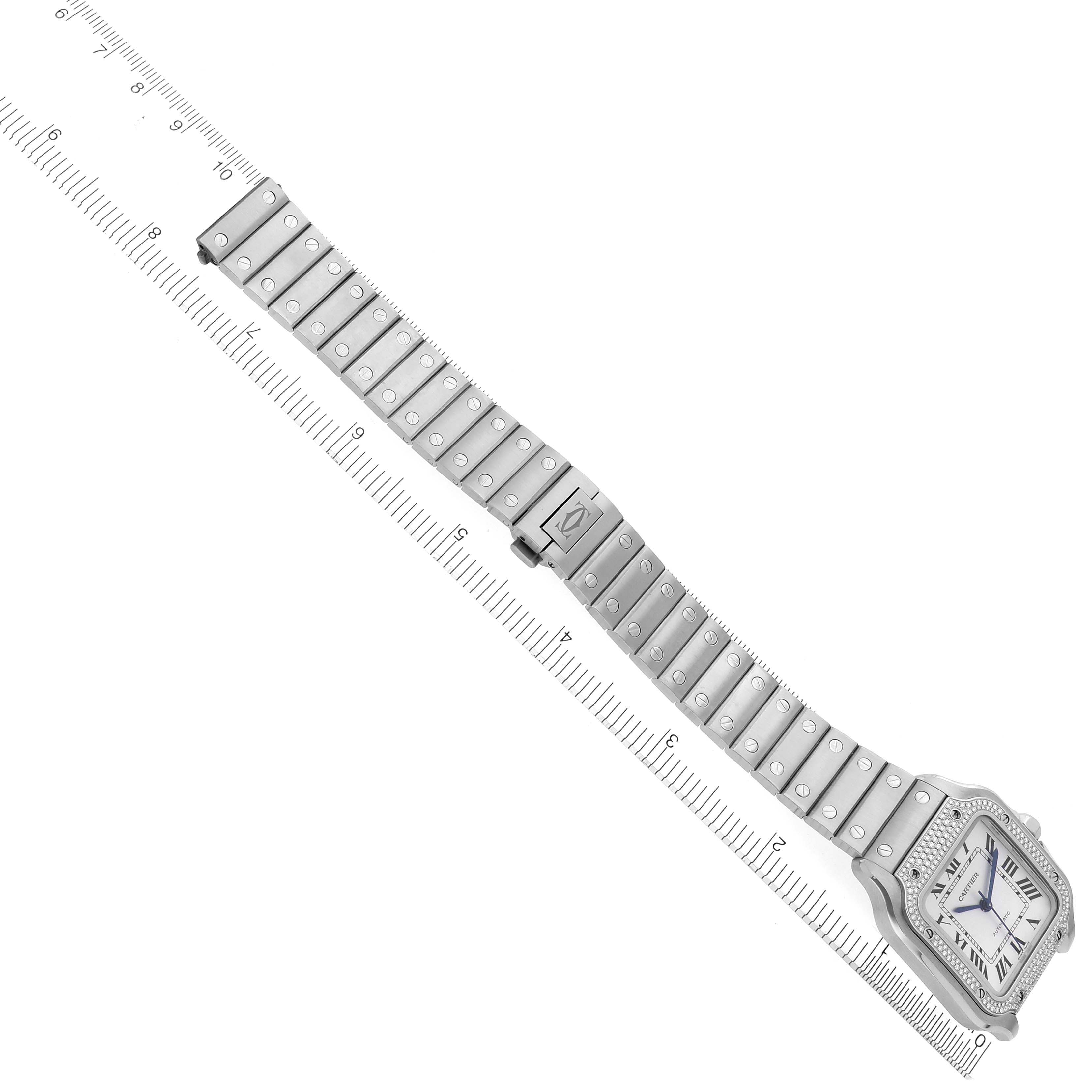 The Cartier Santos W4SA0005 Men
s Stainless Steel Silver Dial W4SA0005 Men
s Stainless Steel Silver Dial watch is shown flat with a full view of the face and bracelet on a ruler.