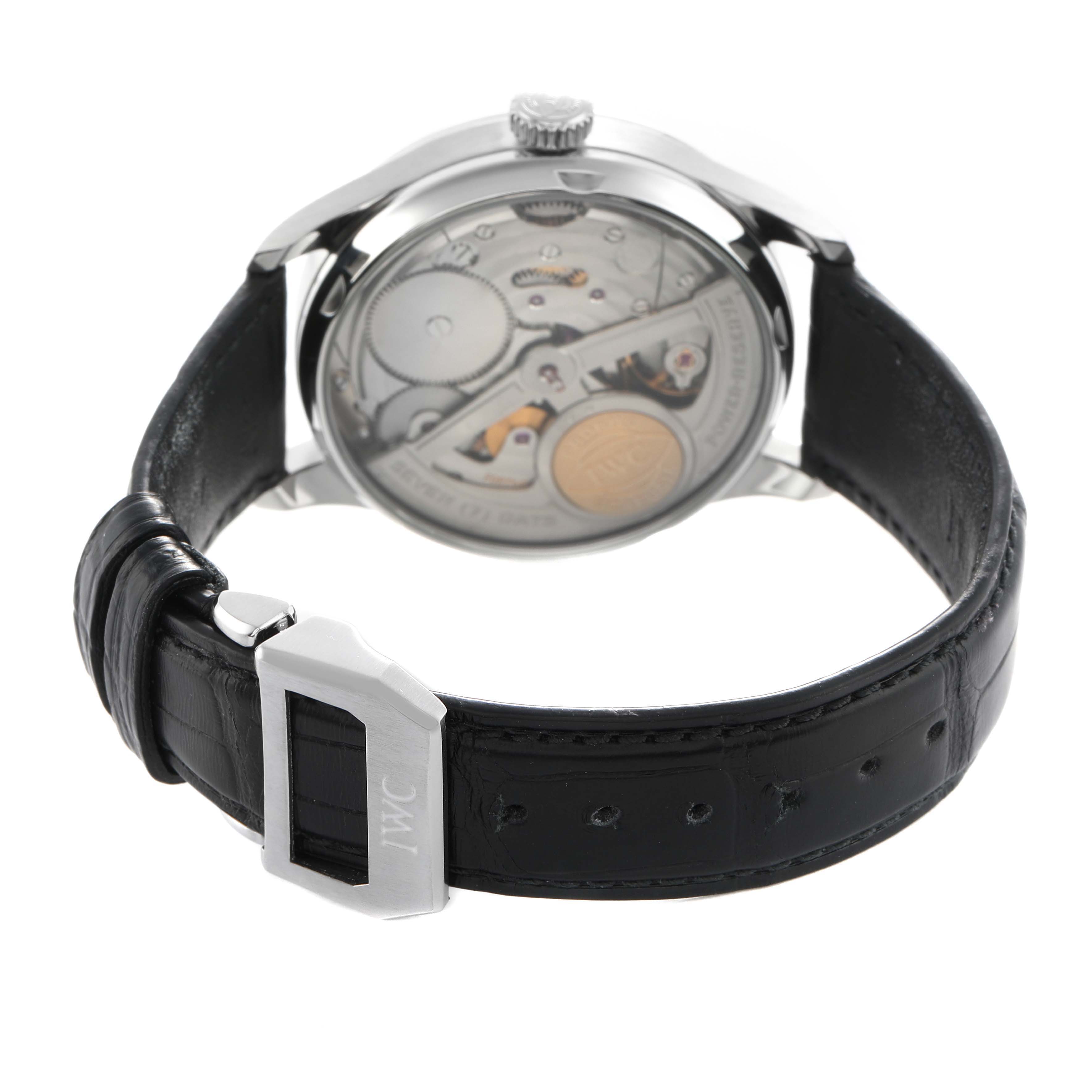 The IWC Portuguese IW500703 Men's Stainless Steel Black Dial watch is shown from the back, displaying its movement and black leather strap with buckle.
