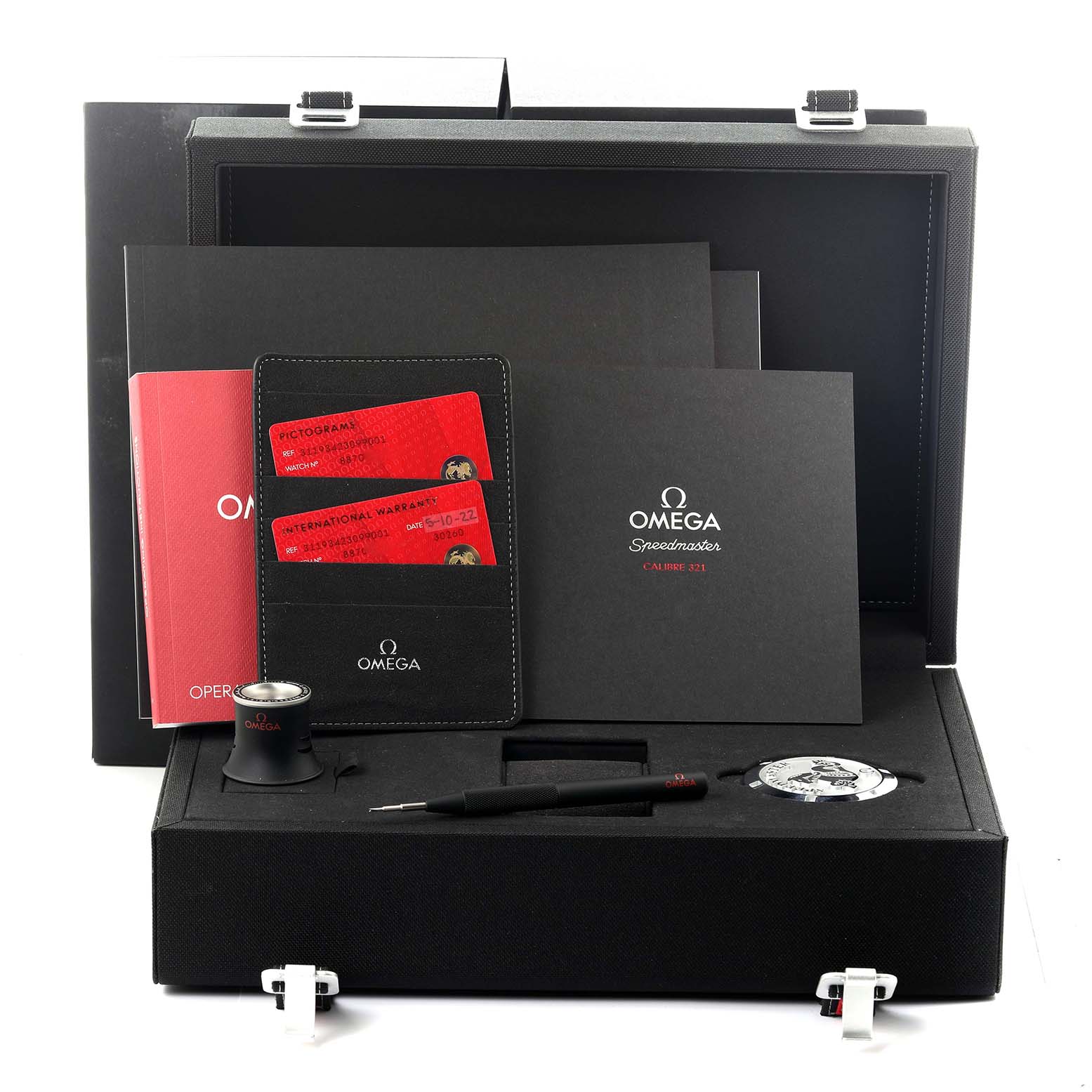 The Omega Speedmaster 311.93.42.30.99.001 Men's Platinum Black Dial 311.93.42.30.99.001 Men's Platinum Black Dial box shows the watch, a magnifier, manual, warranty cards, and a tool from a frontal angle.