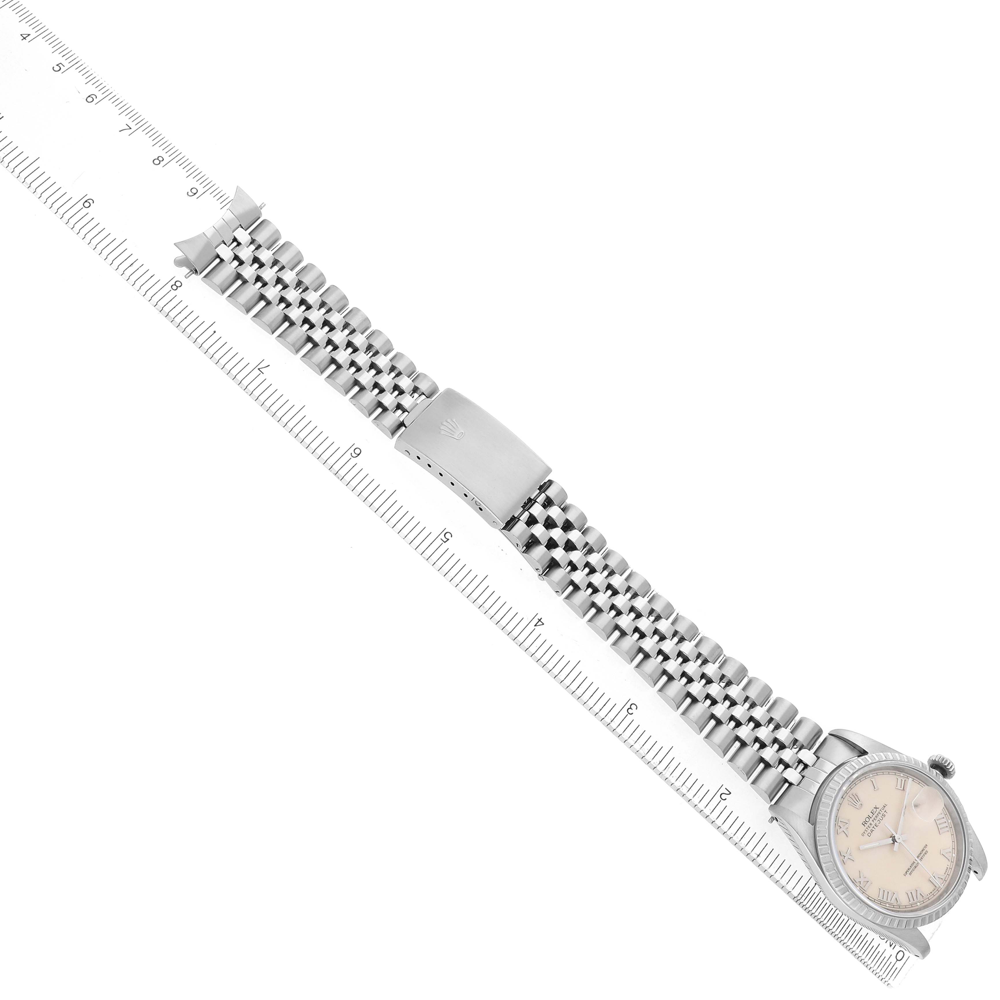 The Rolex Datejust 16220 Men's Stainless Steel Beige Dial watch is shown from a top-down angle, displaying the face, Jubilee bracelet, and clasp, alongside a ruler for scale.
