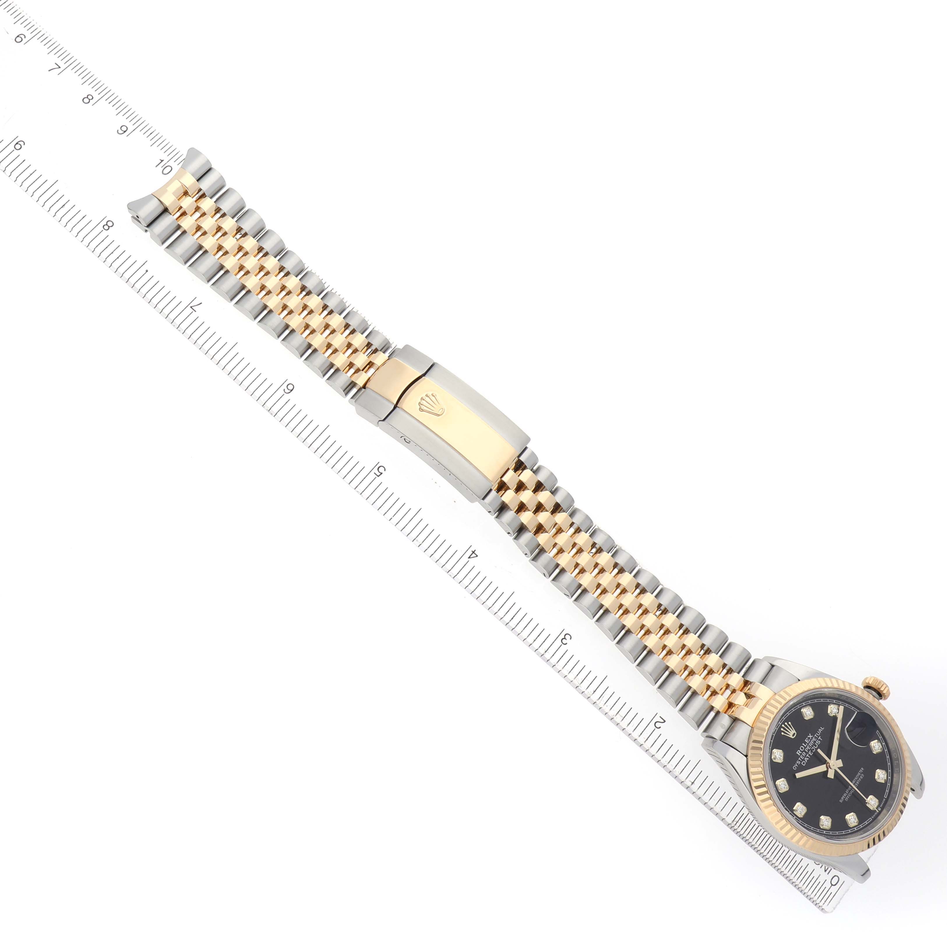 The Rolex Datejust 126233 Men's Steel and Gold (two tone) Black Dial watch is shown from an overhead view, highlighting the bracelet and clasp alongside a ruler for scale.