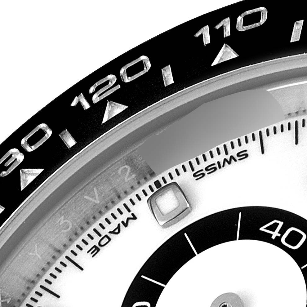 The image shows a close-up of the bezel and part of the dial of a Rolex Daytona 116500 Men's Stainless Steel White Dial 116500 Men's Stainless Steel White Dial watch.