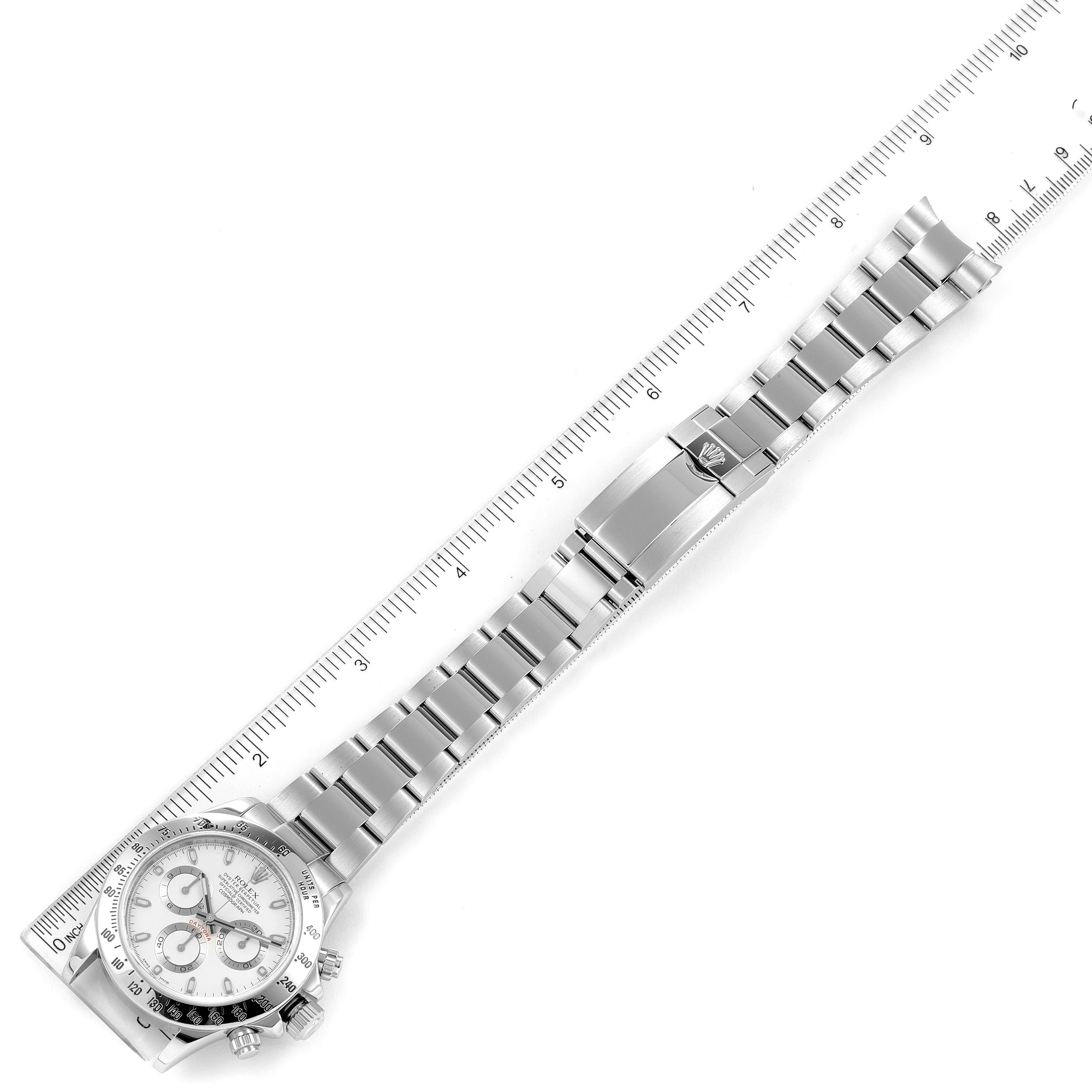 The image shows a Rolex Daytona 116520 Men's Stainless Steel White Dial 116520 Men's Stainless Steel White Dial watch laid flat next to a ruler, displaying the entire bracelet and face.