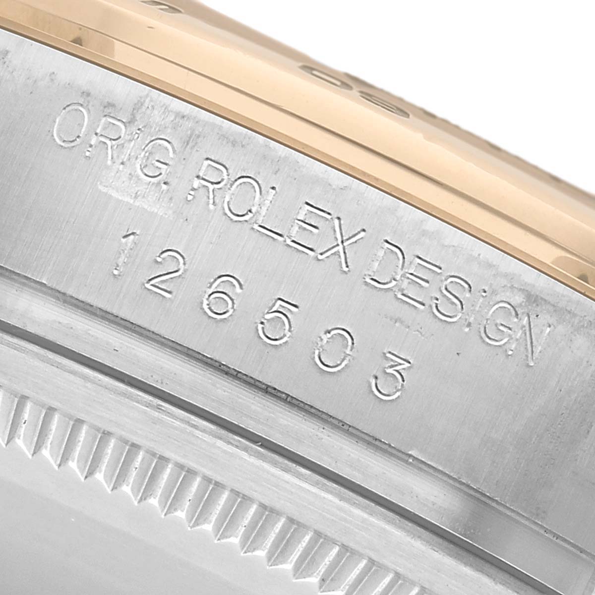 The image shows a close-up of the engraved side of the case of a Rolex Daytona 126503 Men's Steel and Gold (two tone) White Dial, displaying the model number and design details.