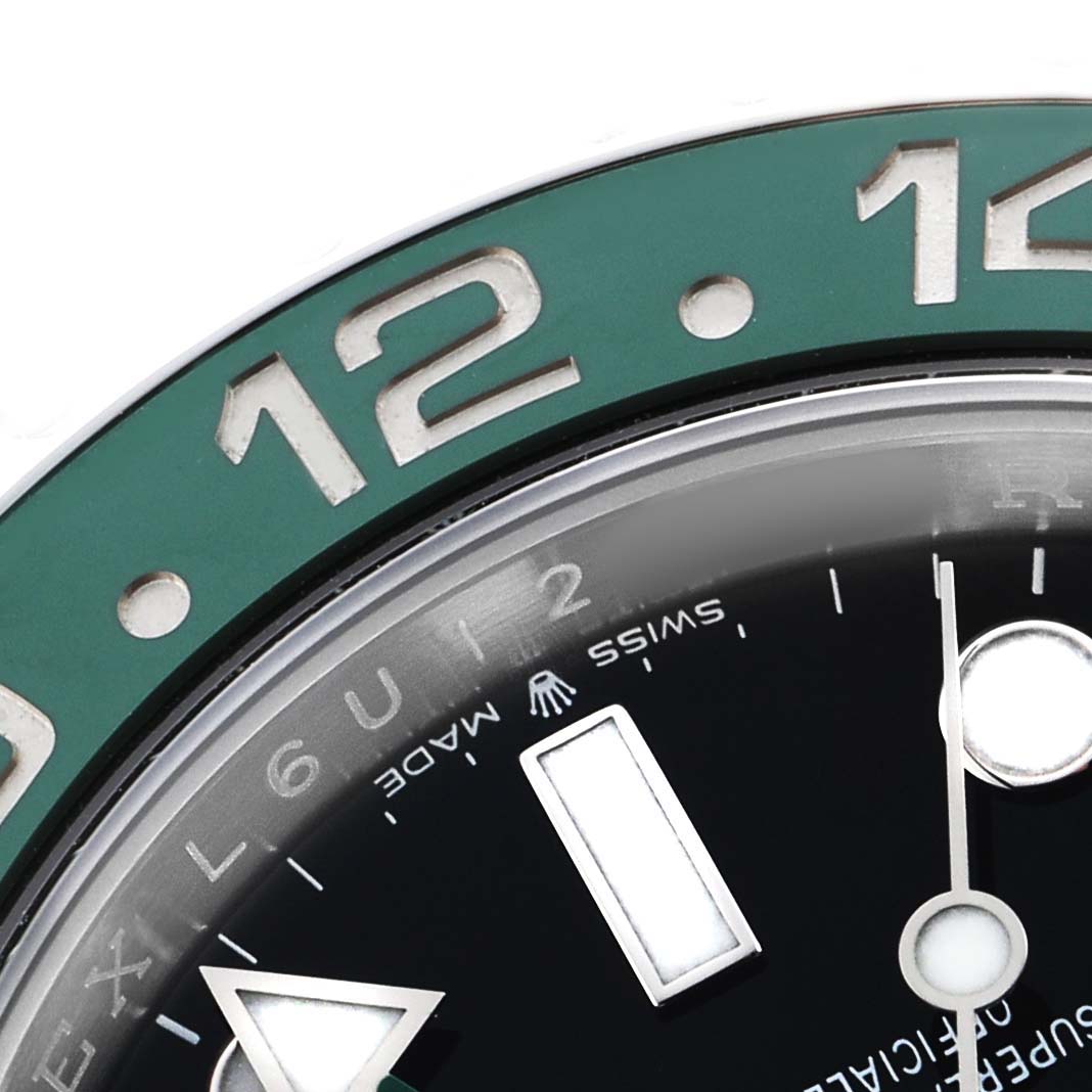 The close-up shows the bezel and part of the dial of the Rolex GMT-Master 126720 Men's Stainless Steel Black Dial, highlighting the 12 and the watch hands.