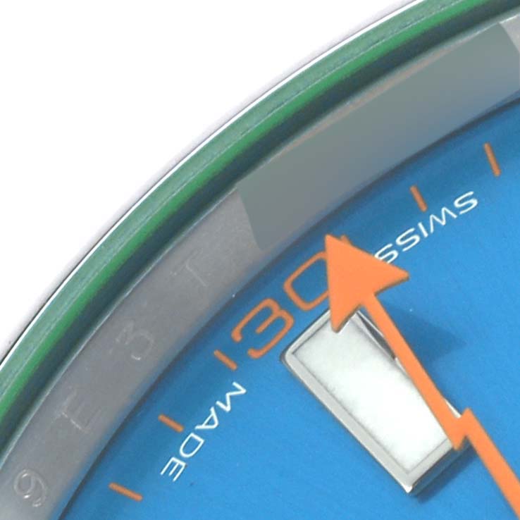 The image shows a close-up of the Rolex Milgauss 116400GV Men
s Stainless Steel Blue Dial 116400GV Men
s Stainless Steel Blue Dial watch face, focusing on the hour marker, orange second hand, and part of the green bezel.