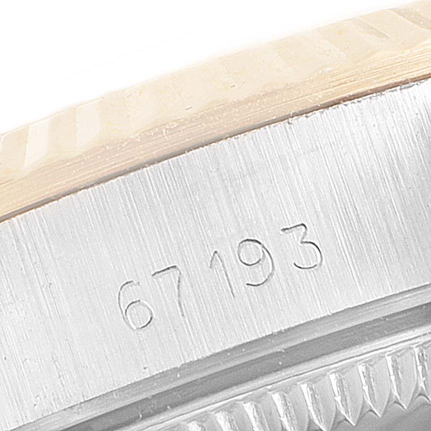This close-up image shows the side of a Rolex Oyster Perpetual 67193 Women's Steel and Gold (two tone) Champagne Dial 67193 Women's Steel and Gold (two tone) Champagne Dial watch with engraved serial numbers and part of the bezel.