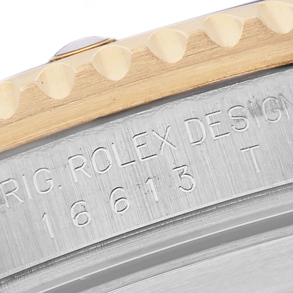 The image shows a close-up of the Rolex Submariner 16613 Men's Steel and Gold (two tone) Blue Dial 16613 Men's Steel and Gold (two tone) Blue Dial's engraved watch bezel and side detailing.