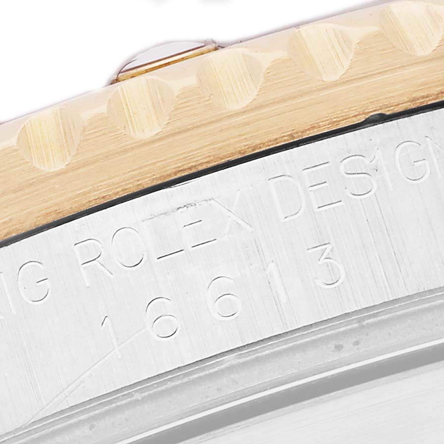 The image shows a close-up of the bezel and engraved edge of the Rolex Submariner 16613 Men's Steel and Gold (two tone) Champagne Dial.