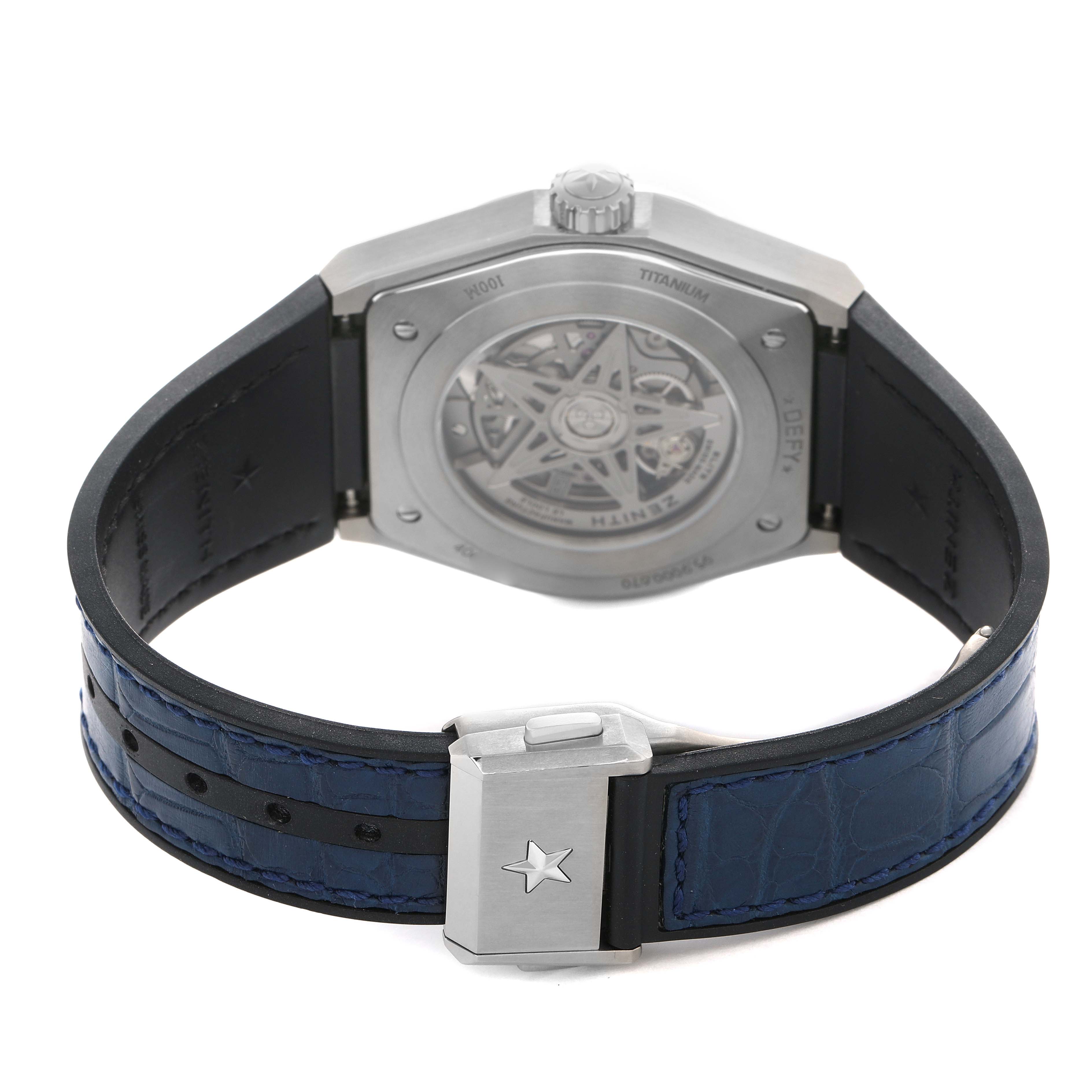 The image shows the back view of the Zenith Defy 95.9000.670/51 Men's Titanium Blue Dial watch with its open case back, visible rotor, leather strap, and clasp.
