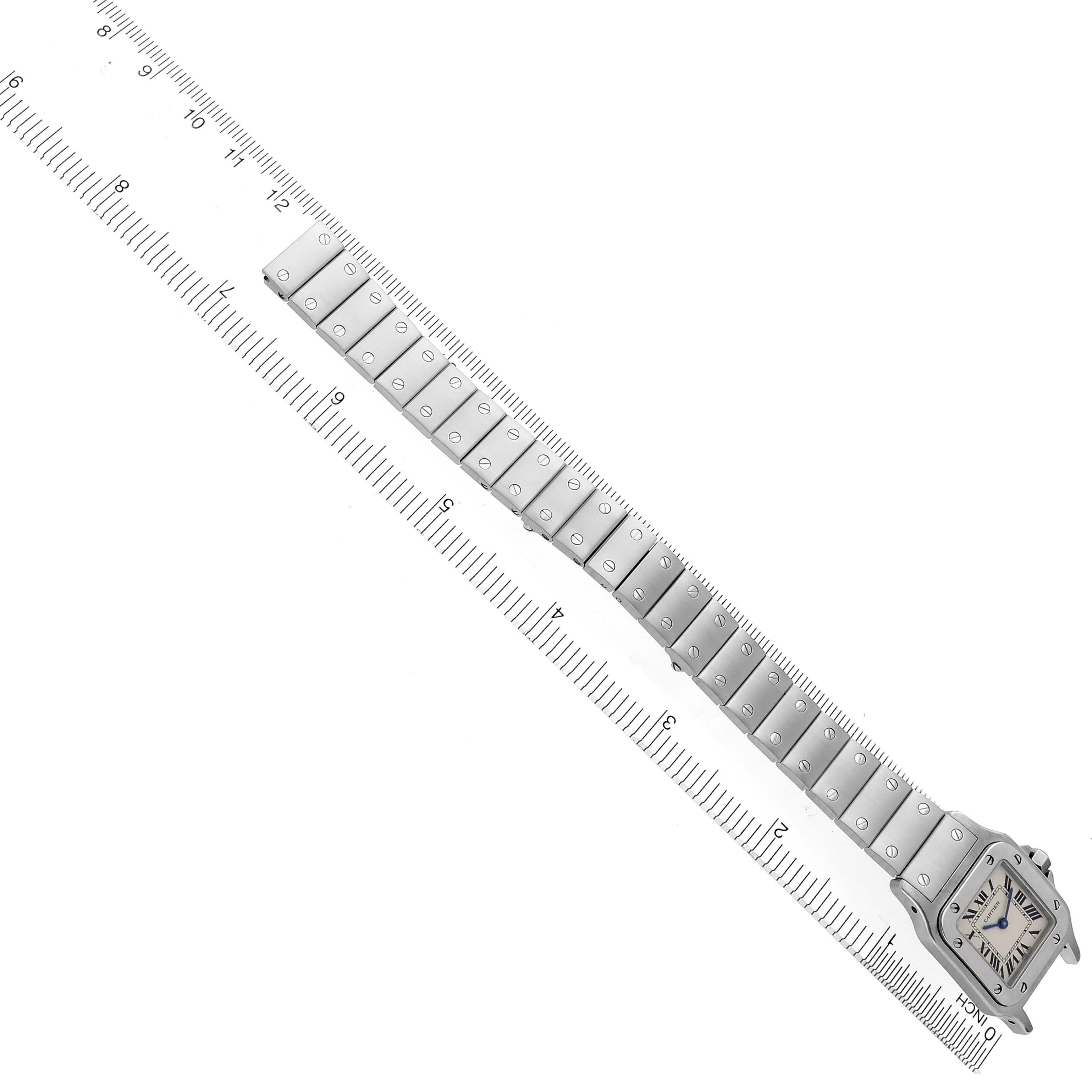 The Cartier Santos W20056D6 Women's Stainless Steel Silver Dial W20056D6 Women's Stainless Steel Silver Dial watch is shown from a top view, highlighting the face and entire bracelet laid alongside a ruler.