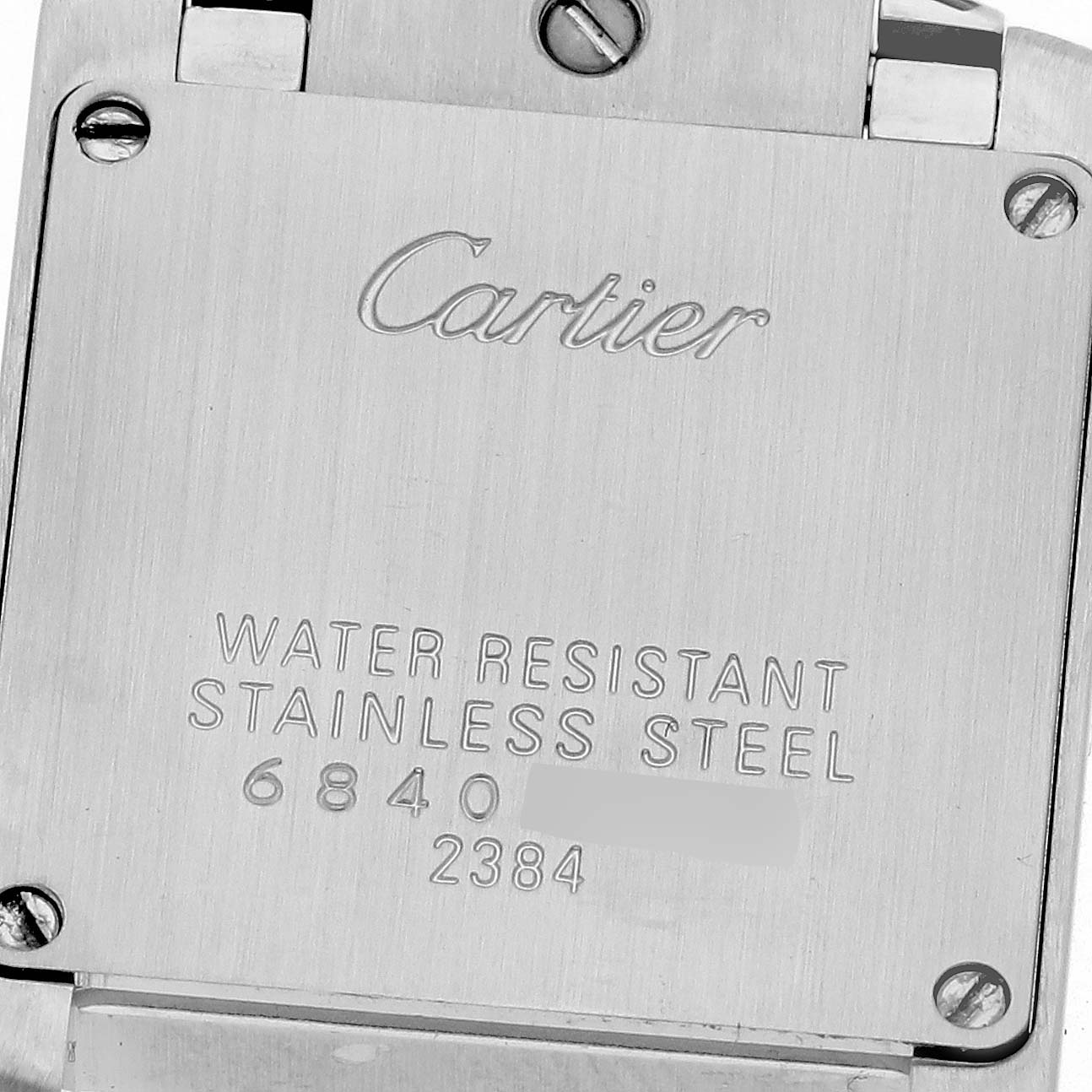 The image shows the back case of a Cartier Tank Française watch with engravings and screws.