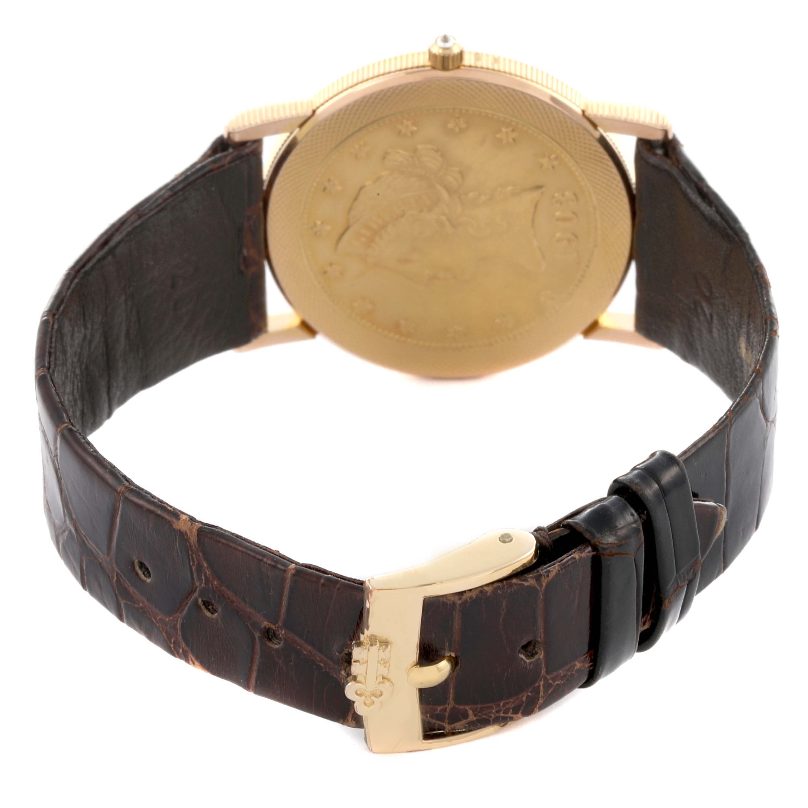 The image shows the back of the Corum Coin Watch 1903 Men's Yellow Gold Yellow Dial 1903 Men's Yellow Gold Yellow Dial, displaying its coin-style case and brown leather strap with a gold buckle.