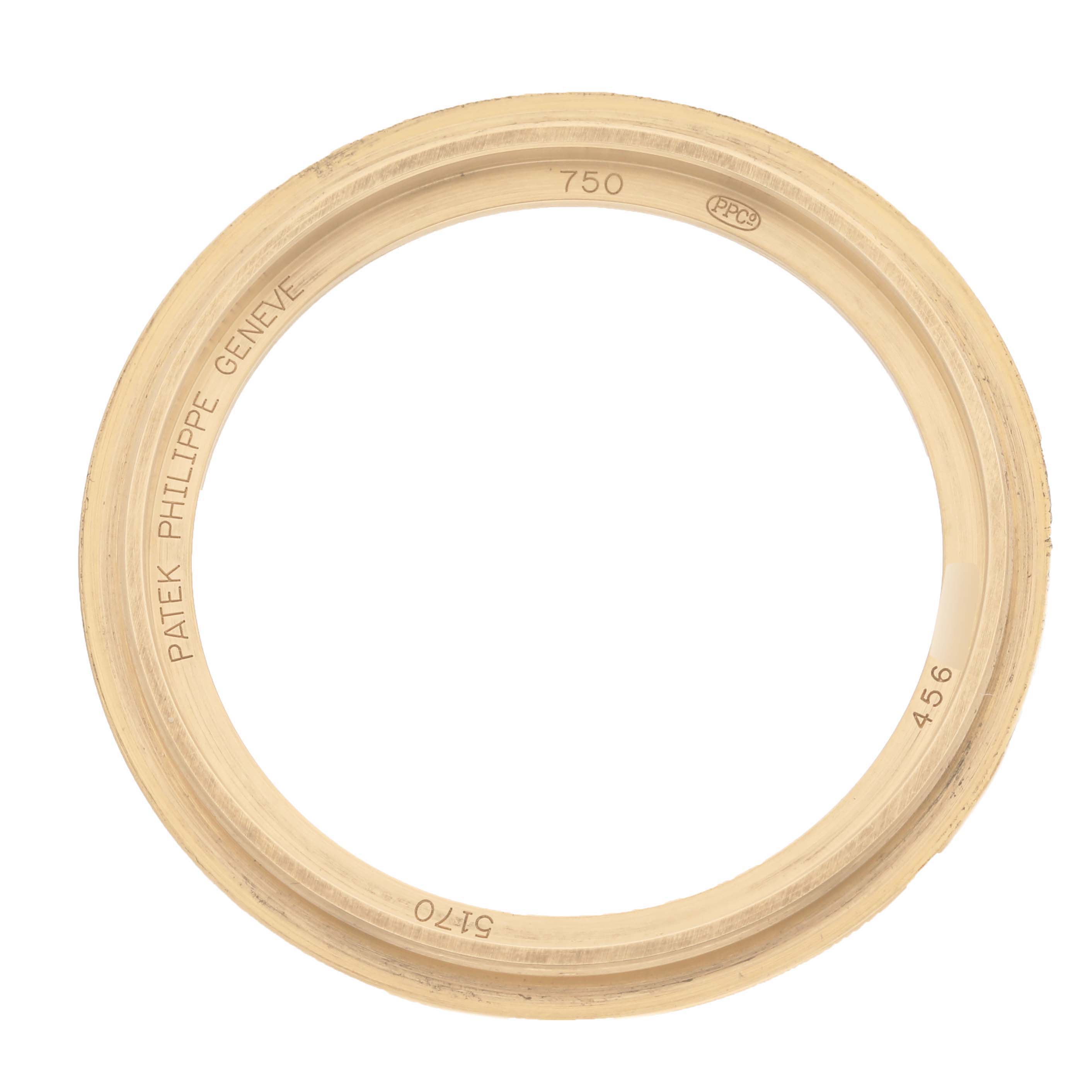 The image shows a gold bezel ring of the Patek Philippe Complications 5170J Men's Yellow Gold Silver Dial 5170J Men's Yellow Gold Silver Dial model, viewed from above.