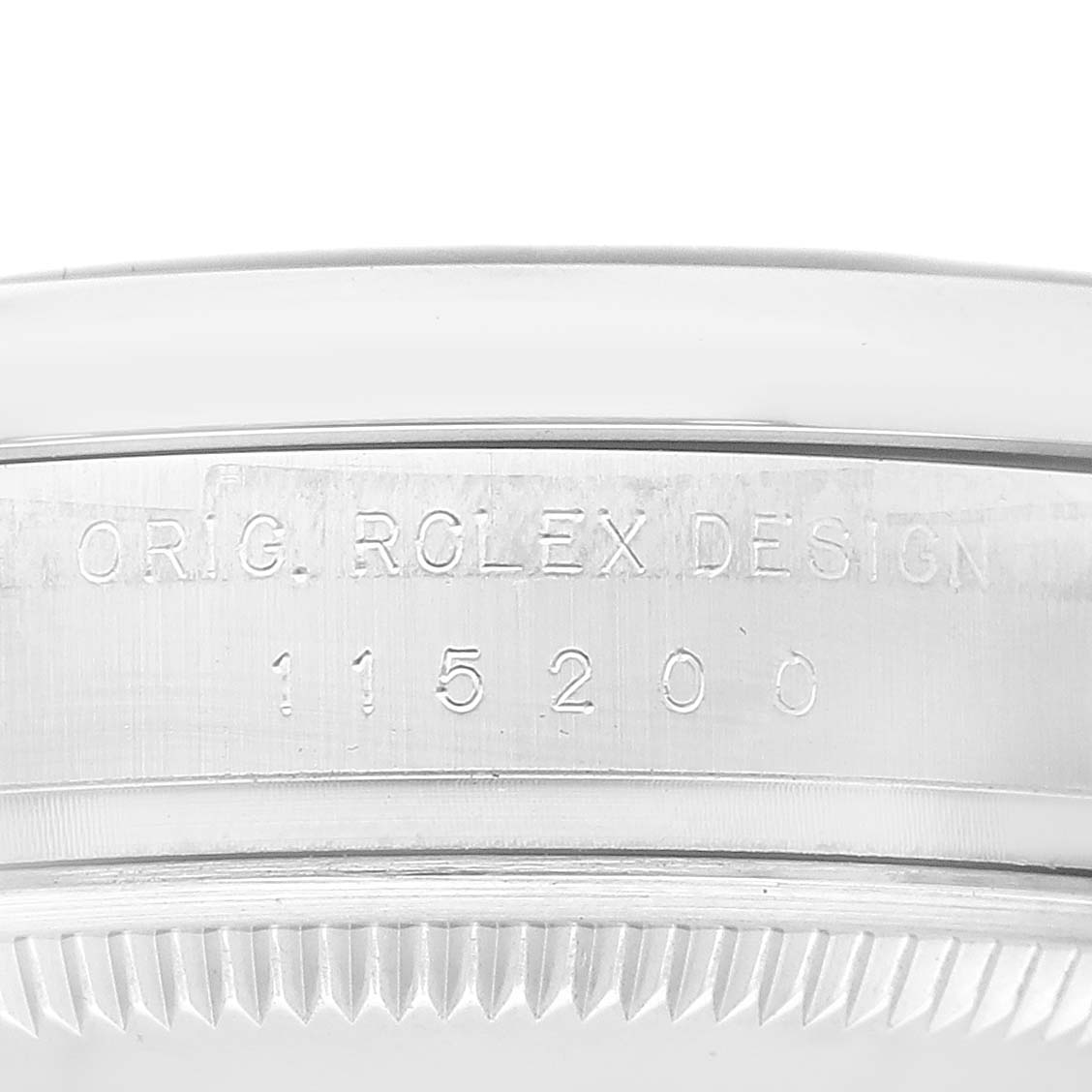 This image shows the side view of the upper case back and edge of the bezel, displaying the model number and "Orig Rolex Design" engraving on the Rolex Date 115200 Men's Stainless Steel Pink Dial 115200 Men's Stainless Steel Pink Dial watch.