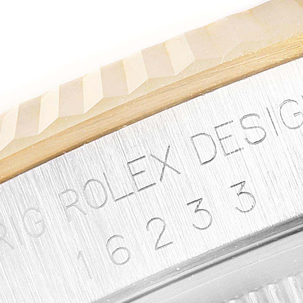This close-up image shows part of the fluted bezel and the "ROLEX" engraving on the casing of a Rolex Datejust 16233 Men's Steel and Gold (two tone) Black Dial 16233 Men's Steel and Gold (two tone) Black Dial watch.