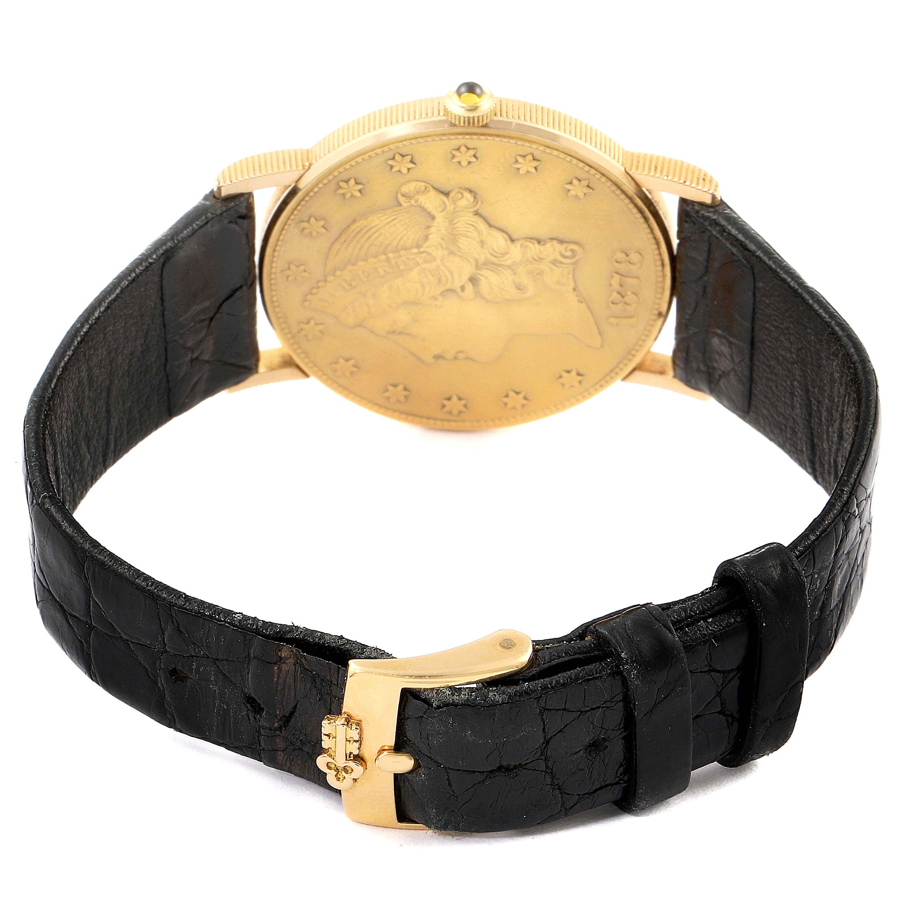 The image shows the back of a Corum Coin Watch 1878 Men's Yellow Gold Black Dial 1878 Men's Yellow Gold Black Dial model, displaying its coin-like case and black leather strap with a gold buckle.