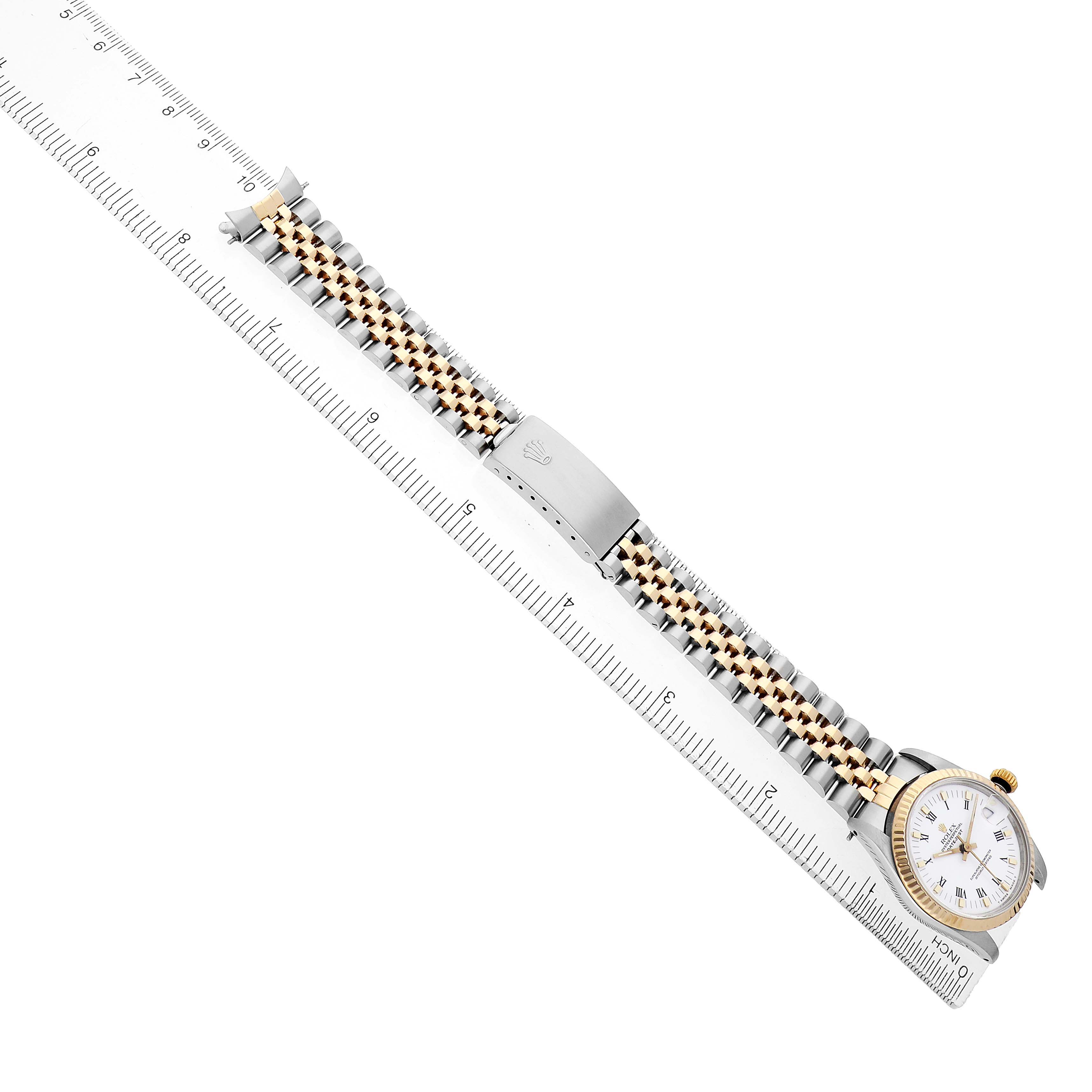 The Rolex Mid-Size 68273 Women's Steel and Gold (two tone) White Dial watch is shown from a top view, displaying its face, bezel, two-tone bracelet, and clasp alongside a ruler for scale.