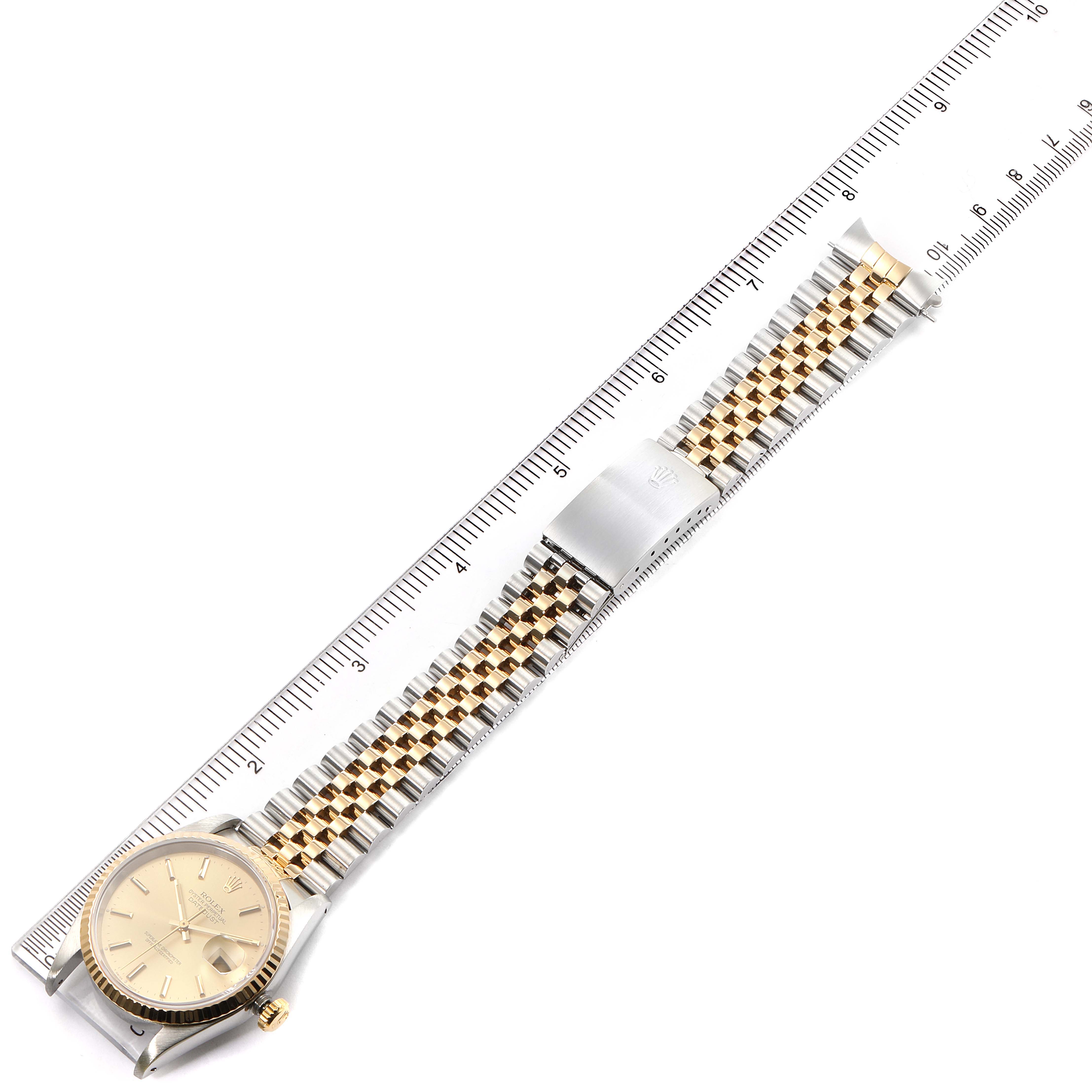 The image shows a Rolex Datejust 16233 Men's Steel and Gold (two tone) Champagne Dial 16233 Men's Steel and Gold (two tone) Champagne Dial watch viewed from the top, highlighting the face, bezel, and two-tone metal bracelet stretched alongside a ruler.