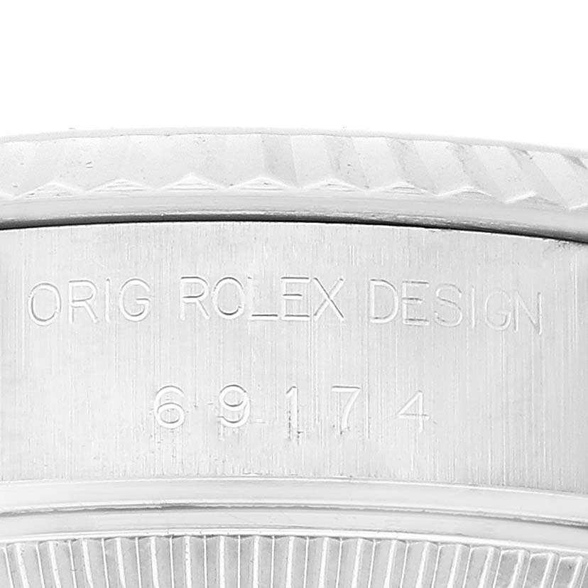 This close-up of the Rolex Datejust 69174 Women's Stainless Steel Silver Dial 69174 Women's Stainless Steel Silver Dial watch shows the engraved "ORIG ROLEX DESIGN" and the serial number on the side of the case.