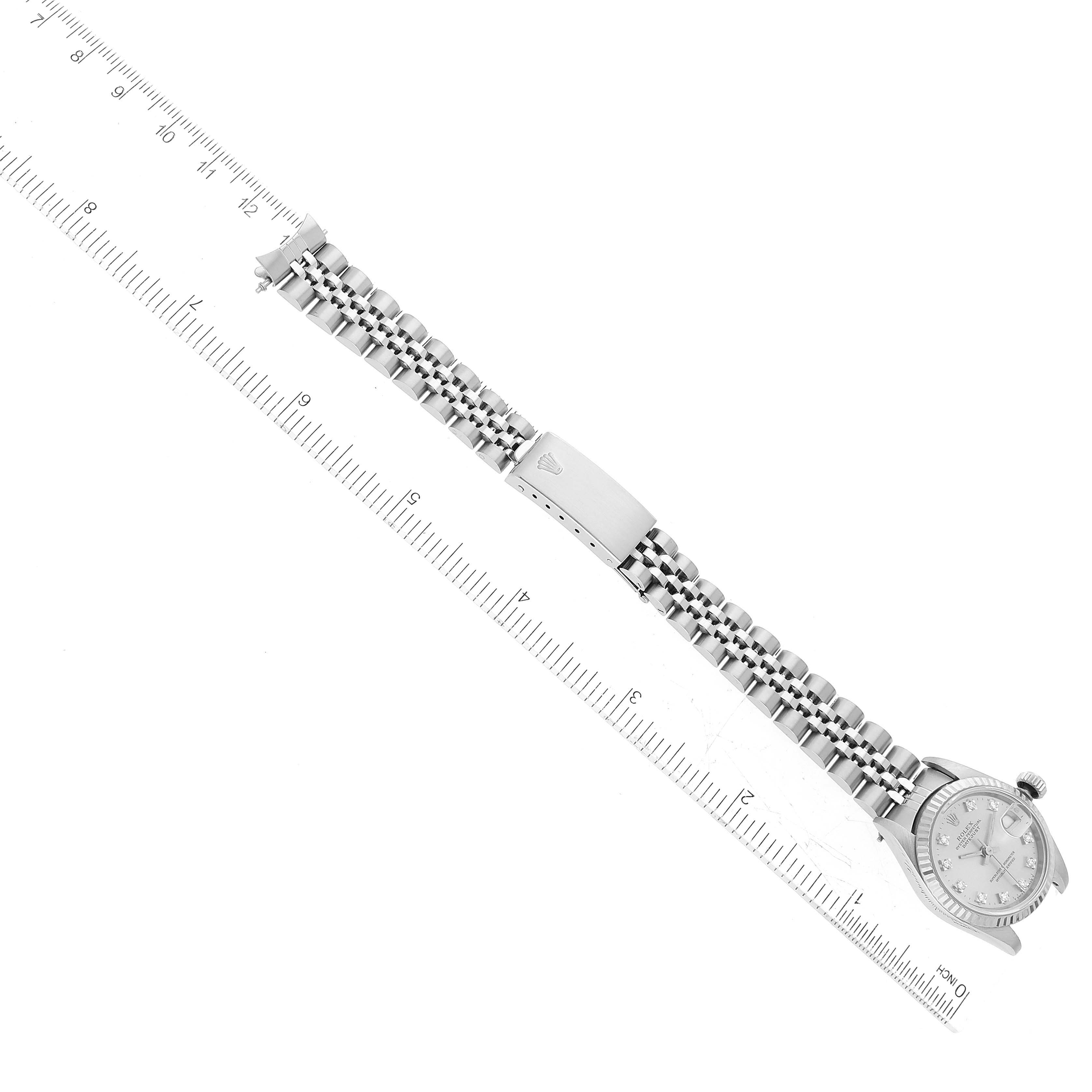 This image shows a Rolex Datejust 69174 Women's Stainless Steel Silver Dial 69174 Women's Stainless Steel Silver Dial watch with a silver dial and Jubilee bracelet, held alongside a ruler, viewed from above.