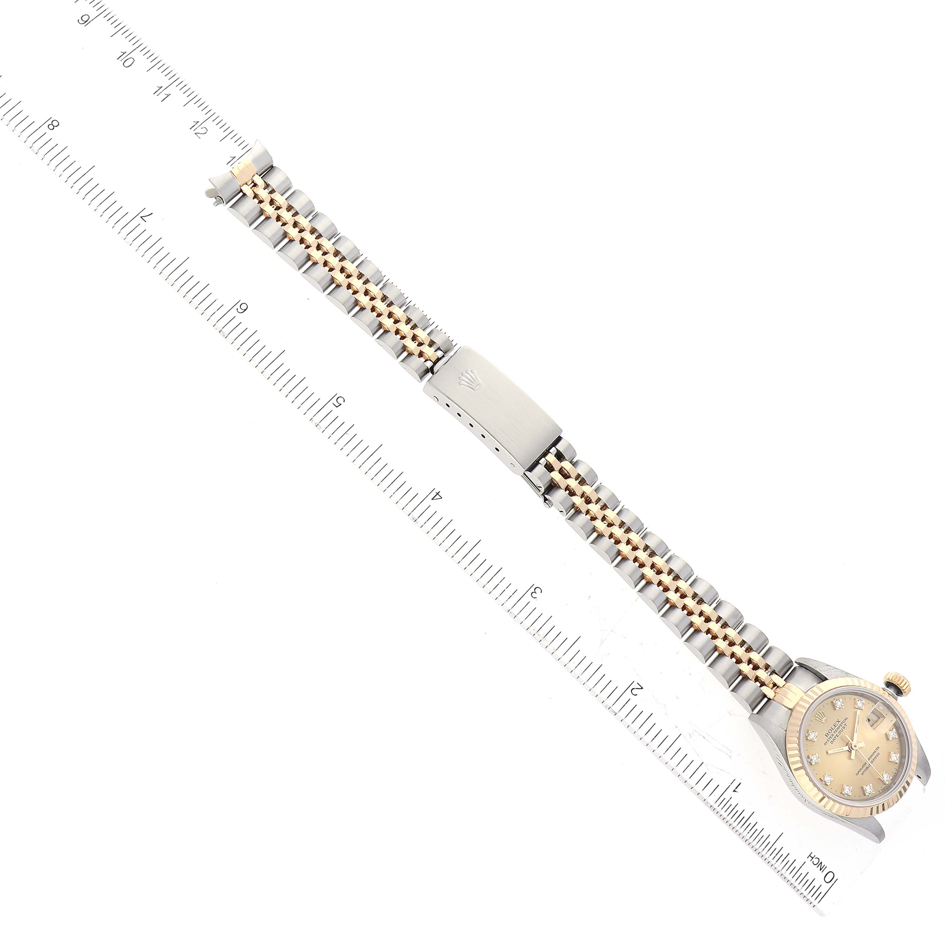 The image shows a Rolex Datejust 69173 Women's Steel and Gold (two tone) Champagne Dial 69173 Women's Steel and Gold (two tone) Champagne Dial model watch laid flat alongside a ruler, highlighting the watch face, bracelet, and clasp.