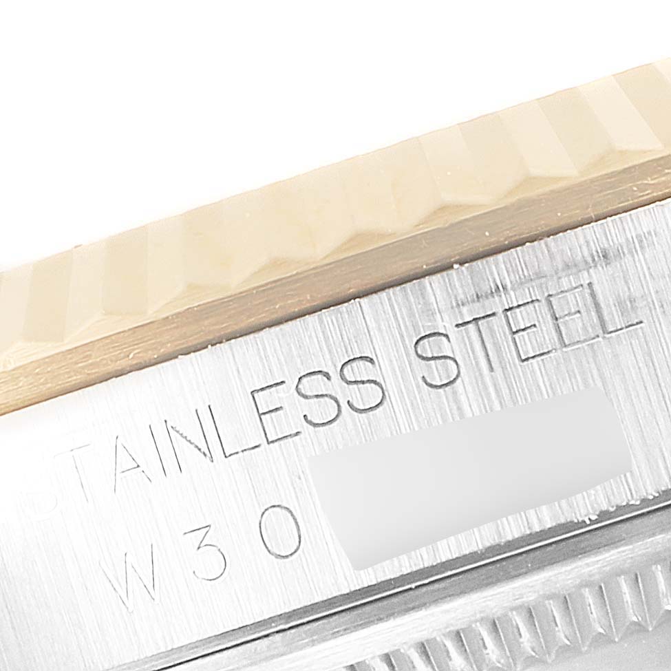 This image shows a macro view of the fluted bezel and part of the case of a Rolex Datejust 16233 Men's Steel and Gold (two tone) Champagne Dial 16233 Men's Steel and Gold (two tone) Champagne Dial watch, revealing the "stainless steel" engraving.