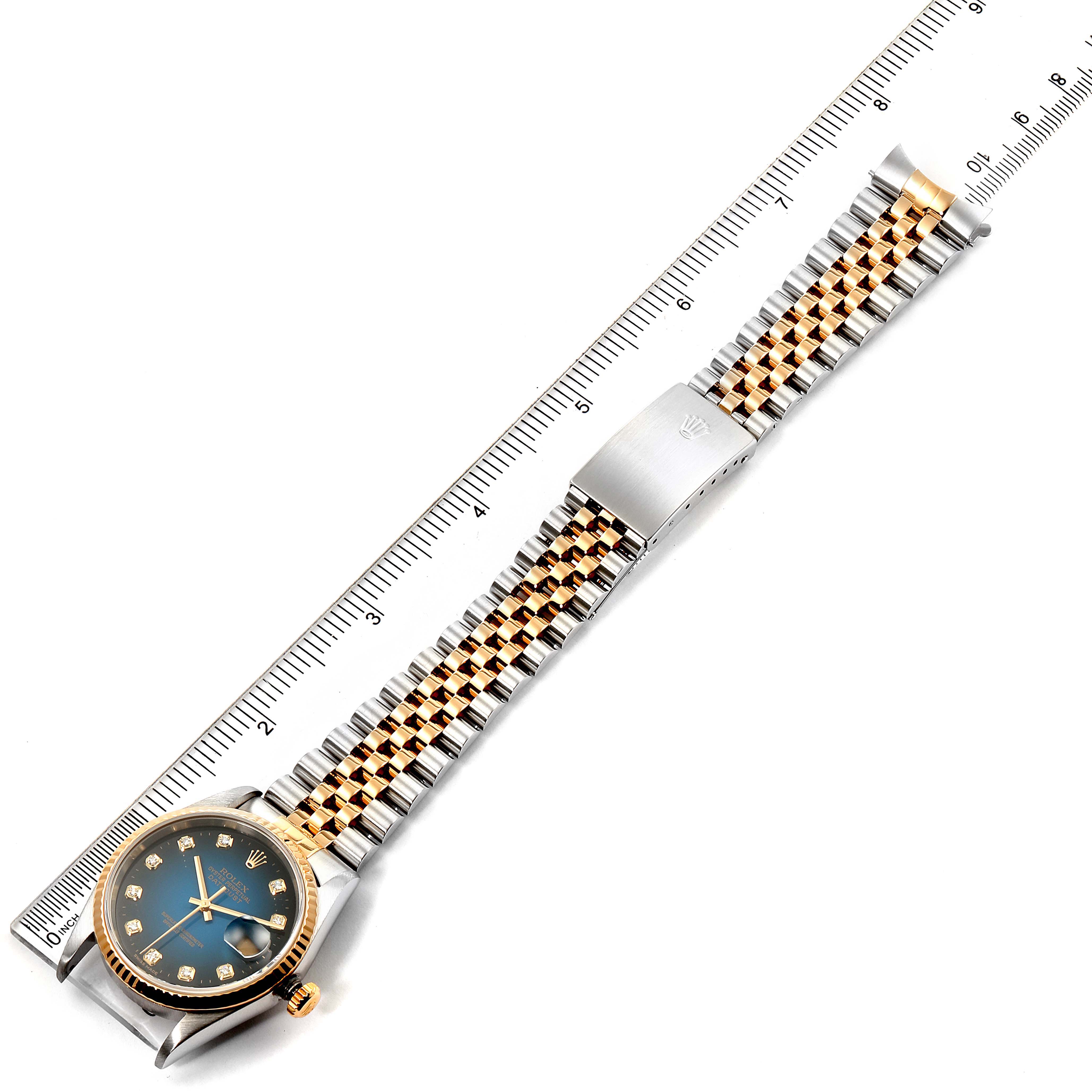 This image shows a Rolex Datejust 16233 Men's Steel and Gold (two tone) Blue Dial 16233 Men's Steel and Gold (two tone) Blue Dial watch laid flat next to a ruler, displaying its entire band and face.