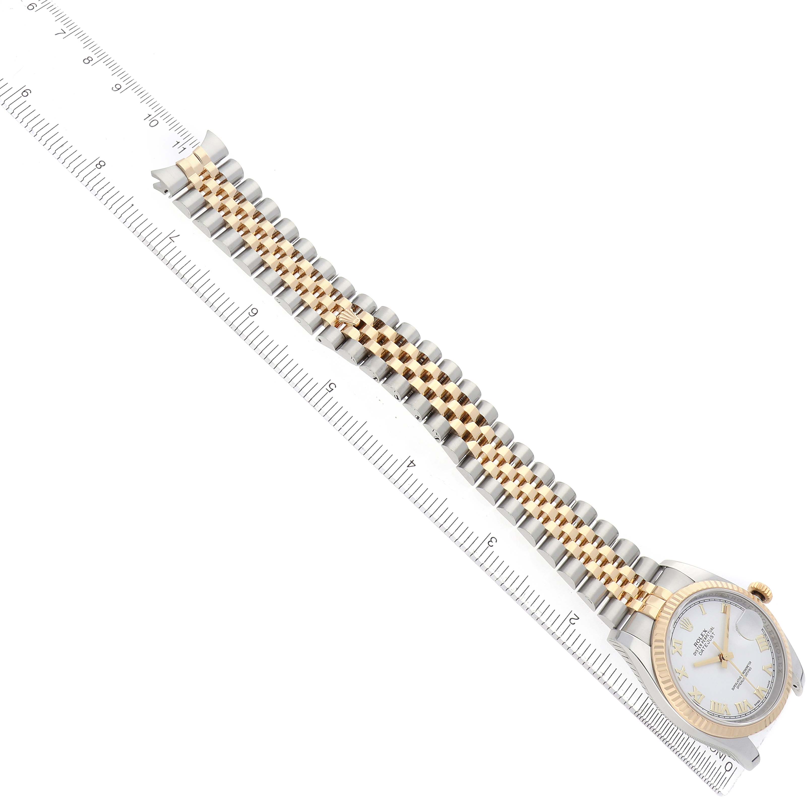 The Rolex Datejust 116233 Men's Steel and Gold (two tone) White Dial watch is shown at an overhead angle, highlighting the gold and silver bracelet and white dial alongside a ruler.