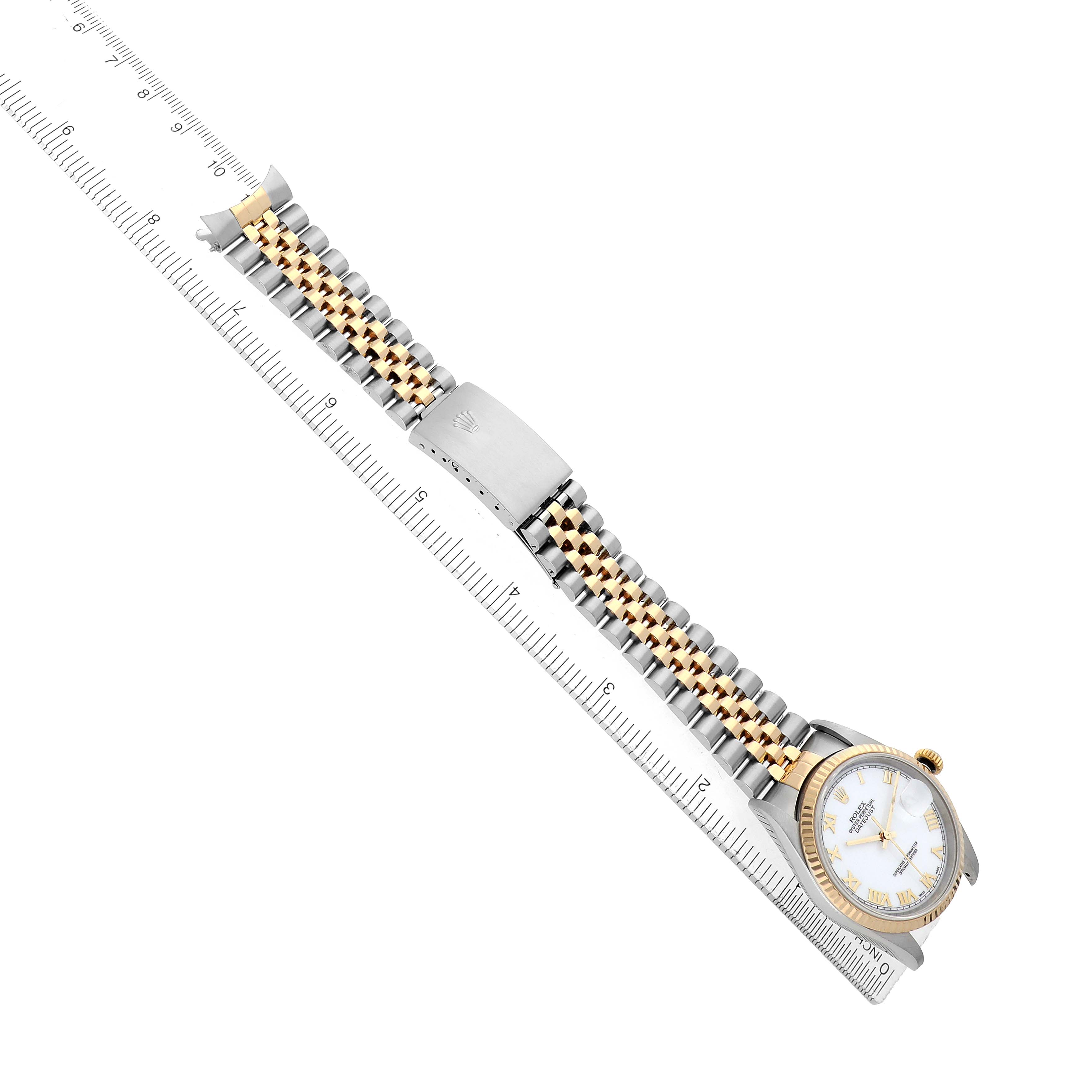 The Rolex Datejust 16233 Men's Steel and Gold (two tone) White Dial watch is shown from an overhead angle with a focus on its strap and clasp, alongside a ruler for scale.